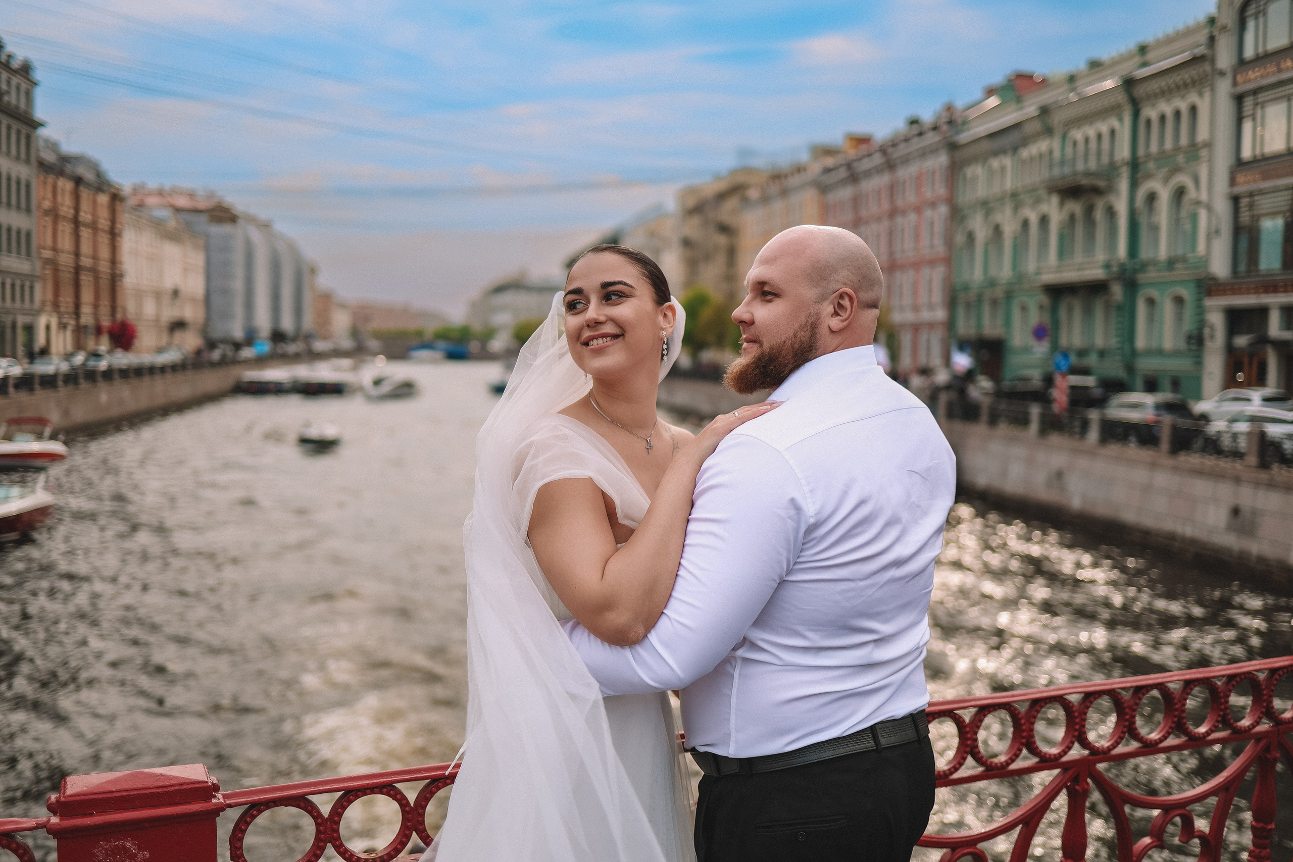 Обнимающиеся молодожены на мосту на фоне набережной канала Грибоедова