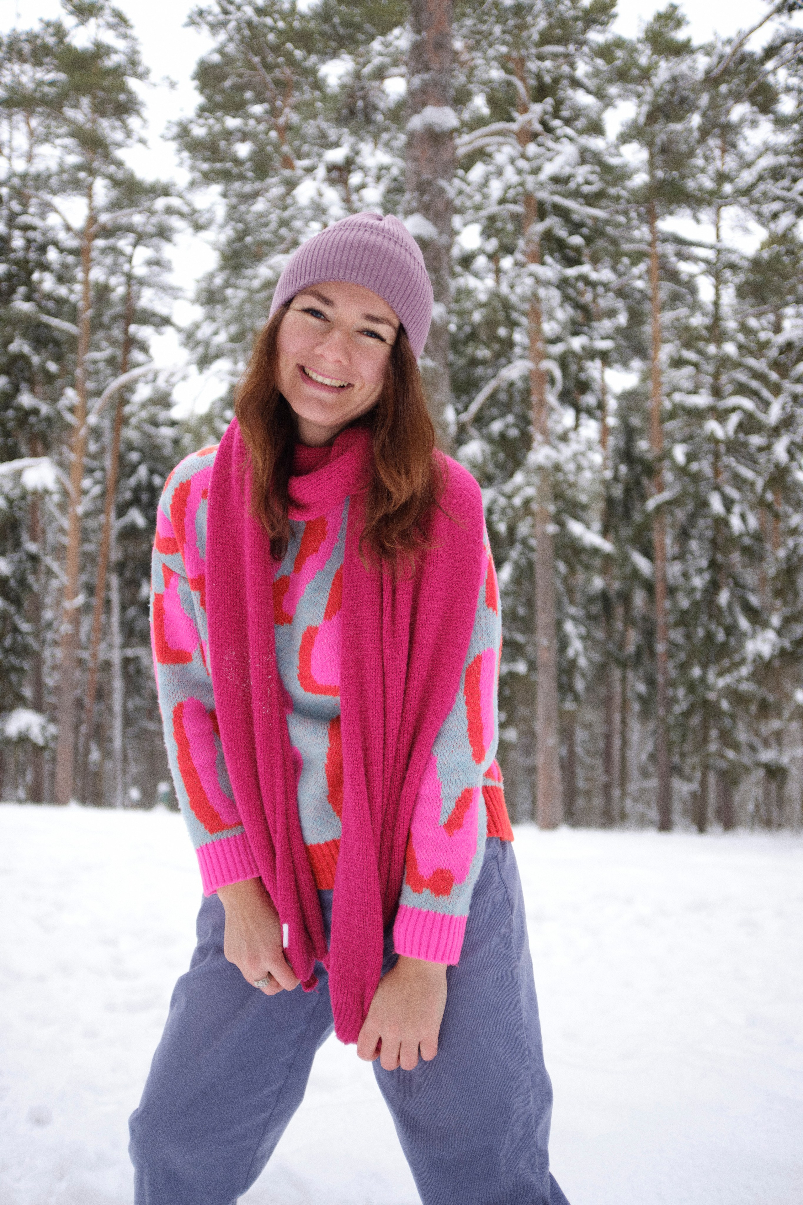 Женщина в ярком шарфе без куртки в зимнем лесу