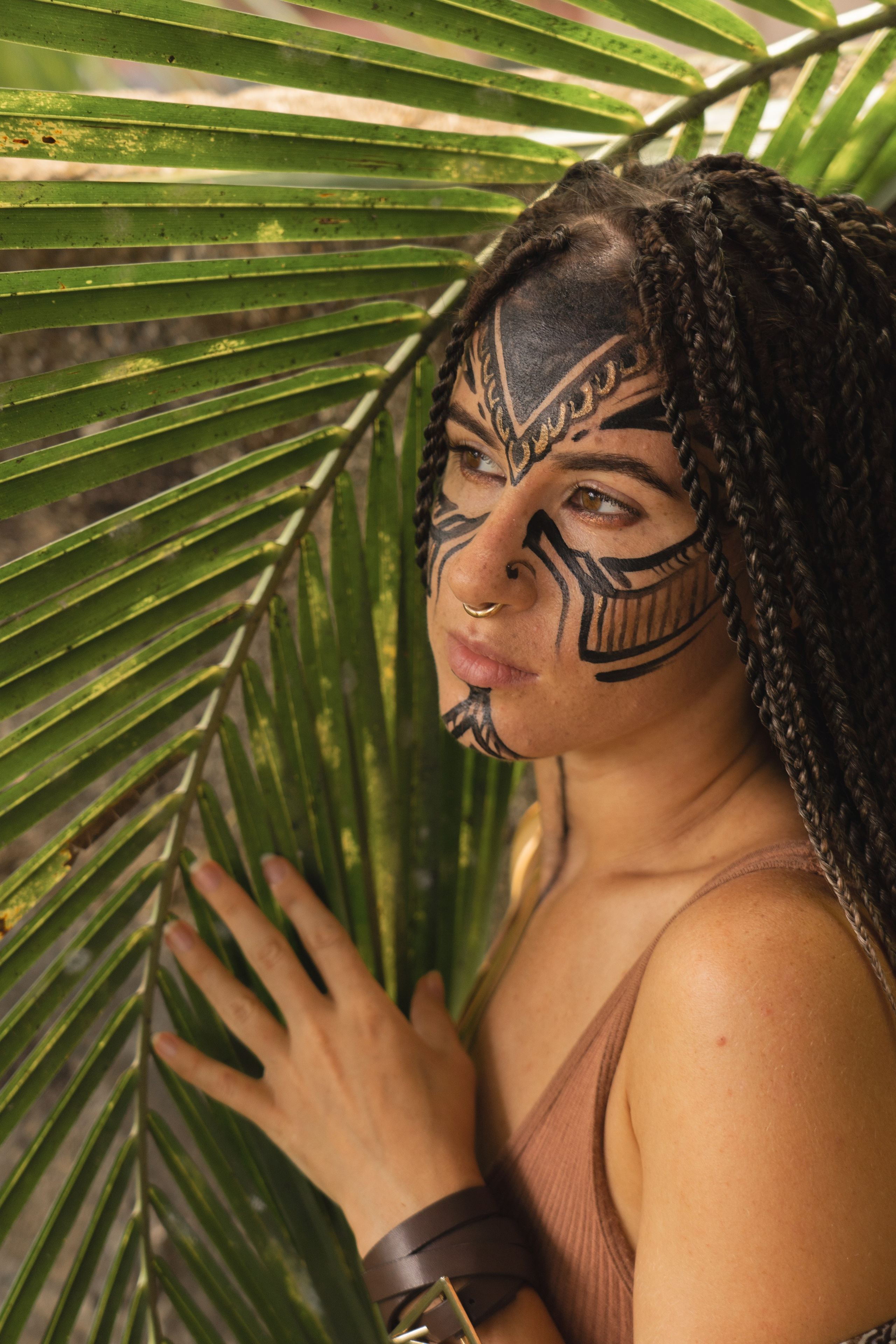 a girl with braids and face paint among trees and exotic plants