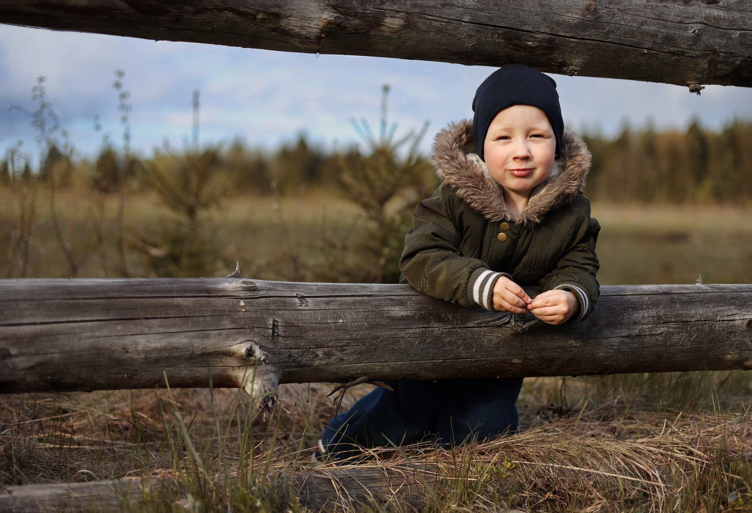 фотосессия на природе в поле ребенок рядом с деревянным забором 