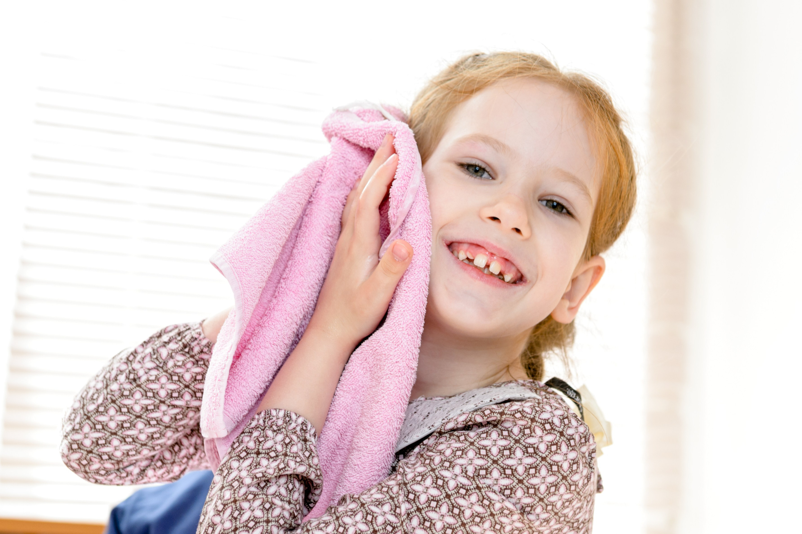 Девочка прижимает к щеке розовое полотенце. 