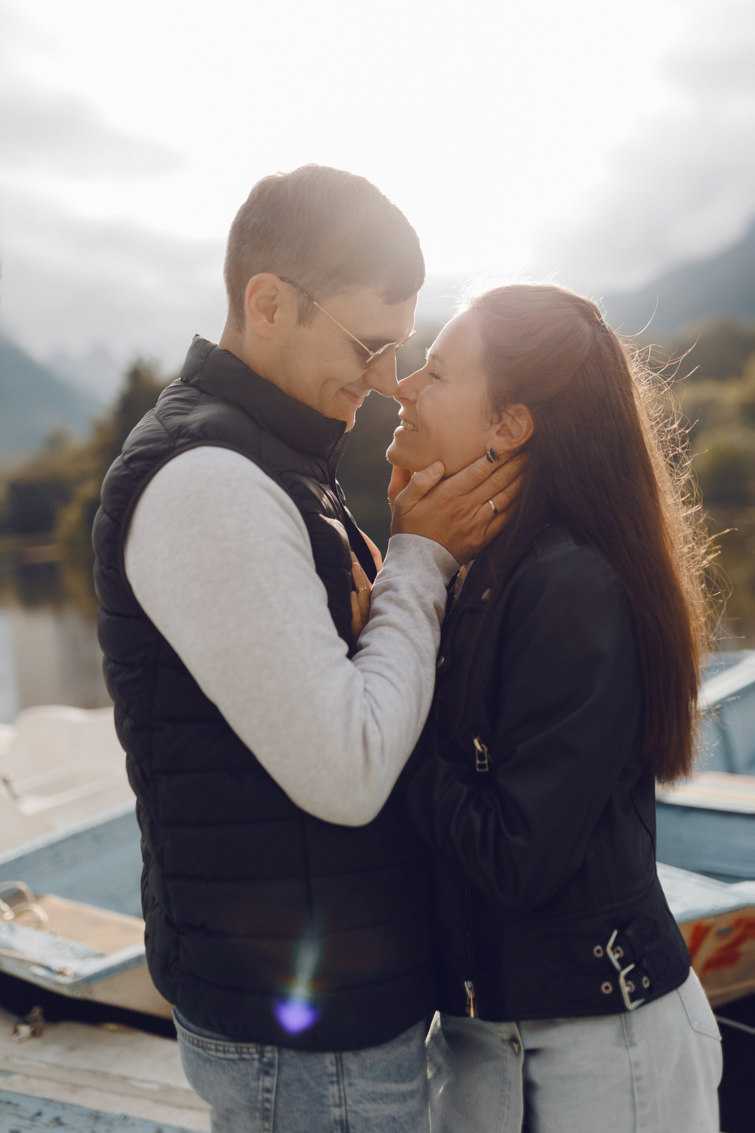 Молодая пара в объятиях смотрит друг на друга на фоне заката в парке. Эмоциональный кадр любви и ожидания.