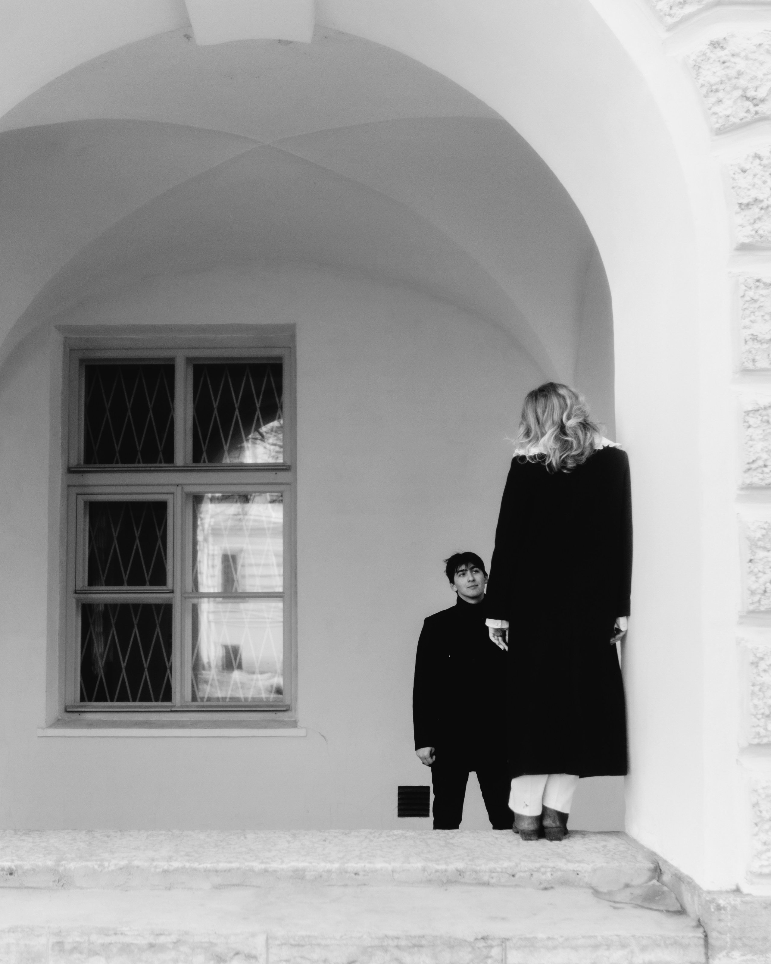 Черно-белая фотосессия пары под аркой, художественная love story съемка в необычной минималистичной городской композиции