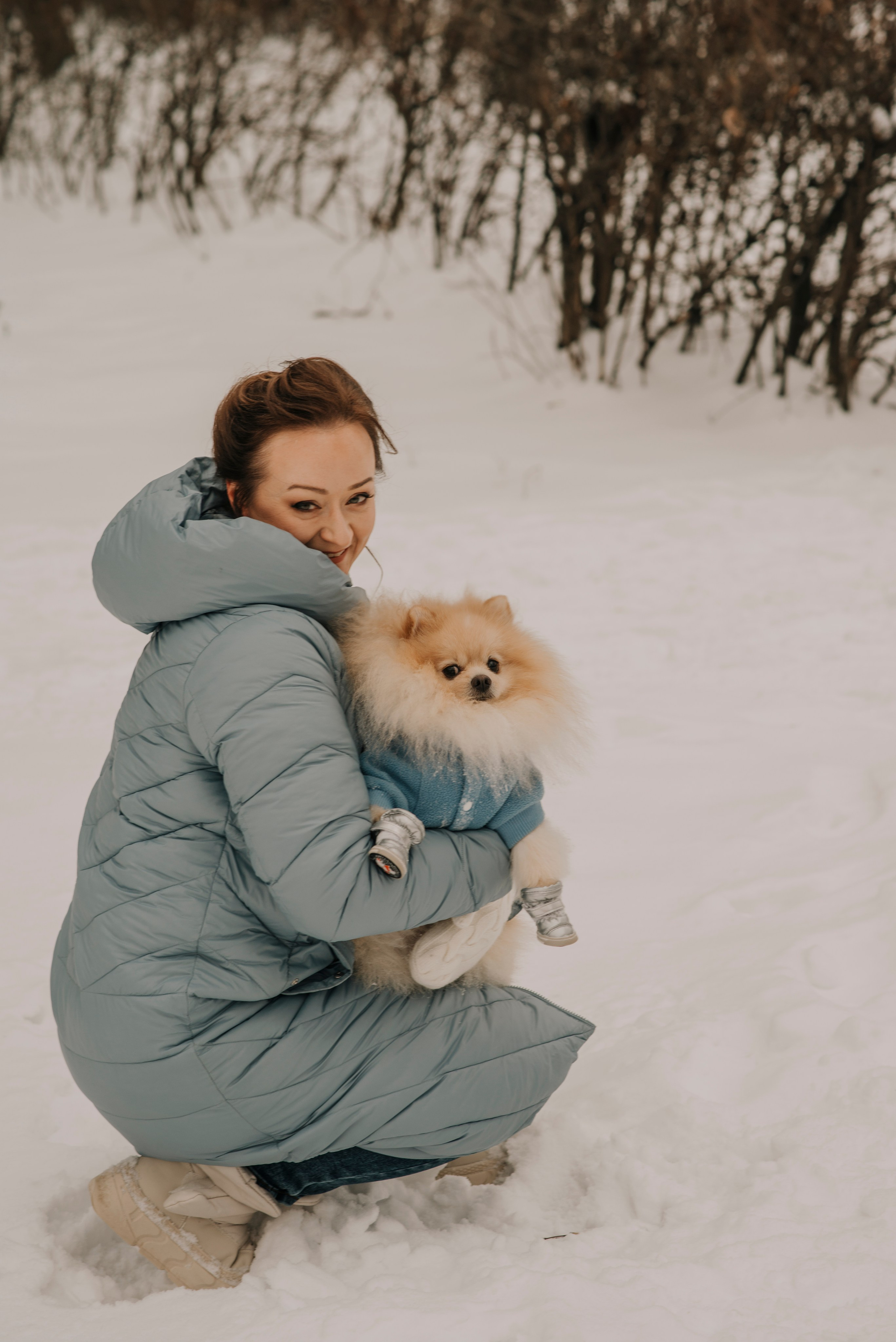 Девушка в голубом пуховике с собачкой шпицем на руках