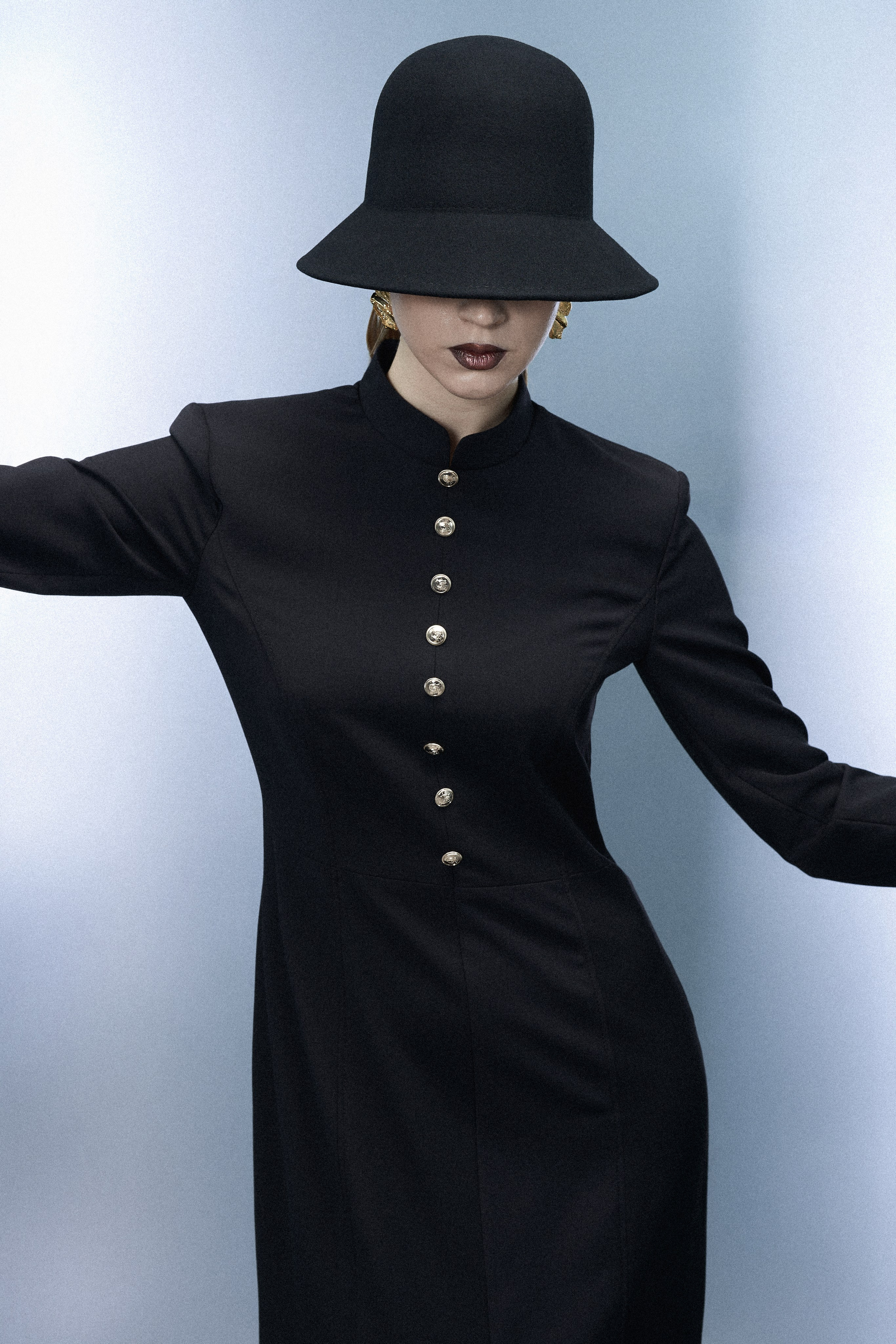 Fashion-портрет модели в чёрном платье с декоративными пуговицами и широкополой шляпой