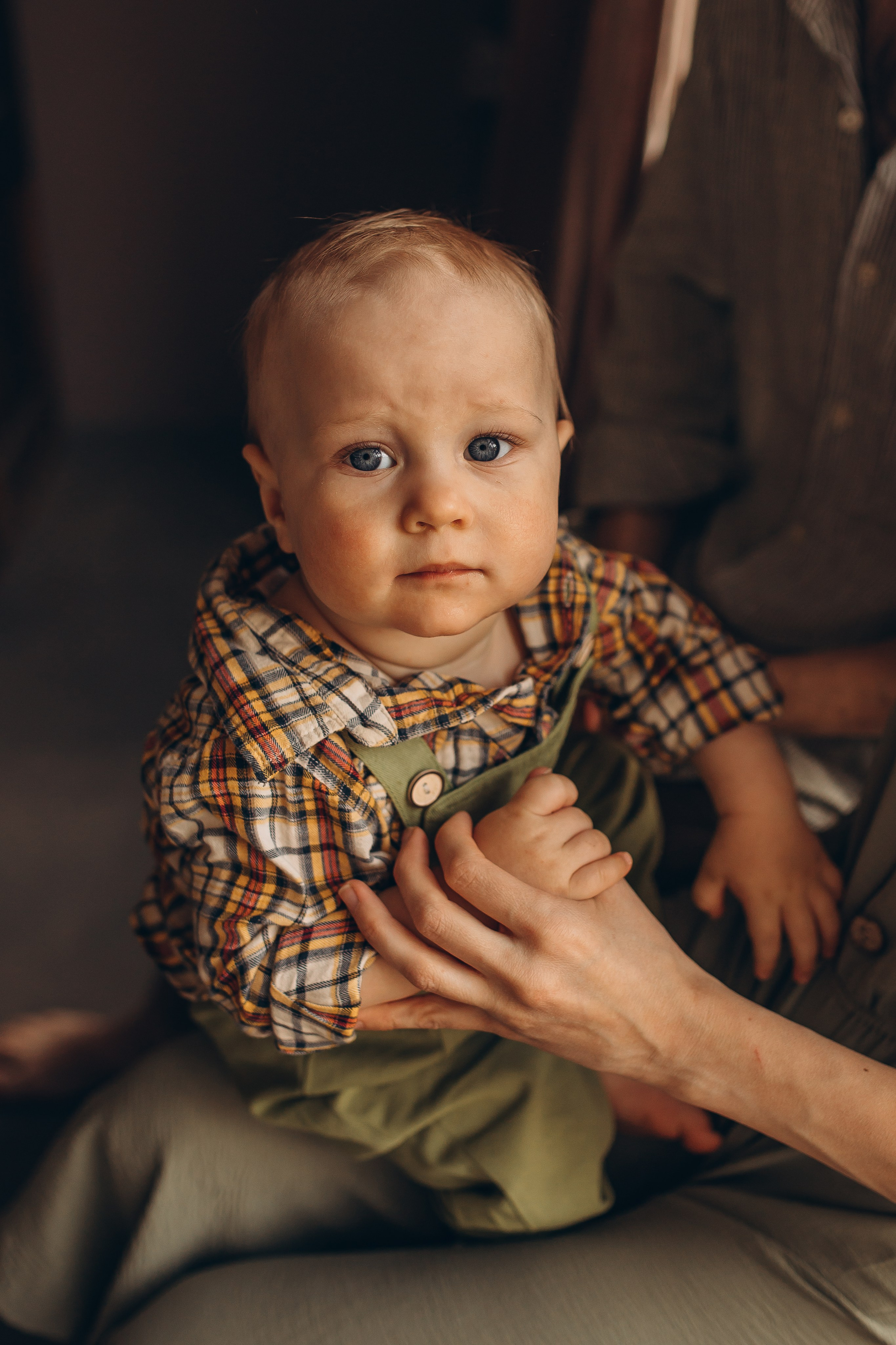 Портрет светловолосого малыша в зеленом комбинезоне на руках у матери. Маруся Самылкина, услуги детского фотографа в Санкт-Петербурге, детский и семейный фотограф спб.