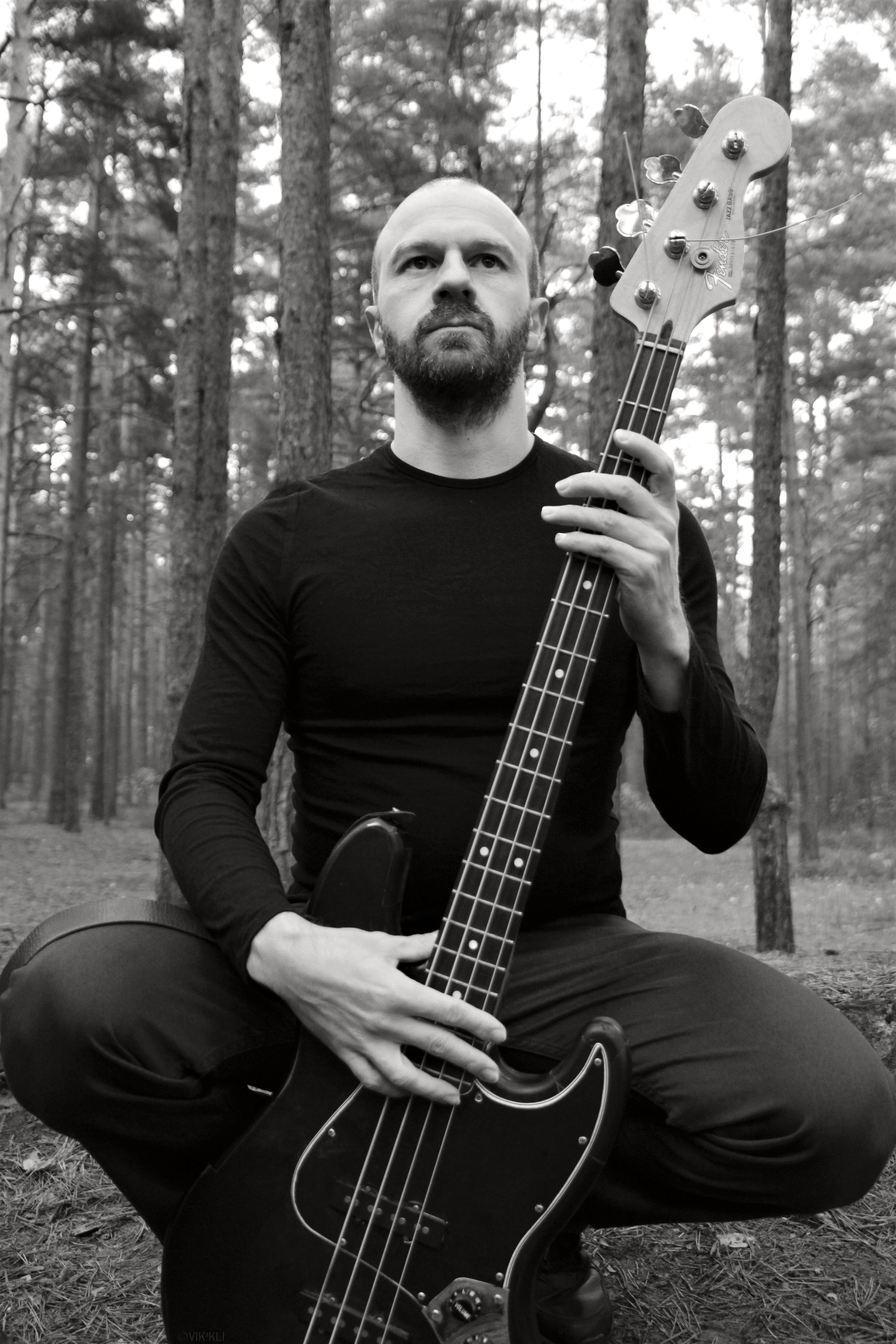 Чёрно-белый портрет мужчины с бас-гитарой в лесу