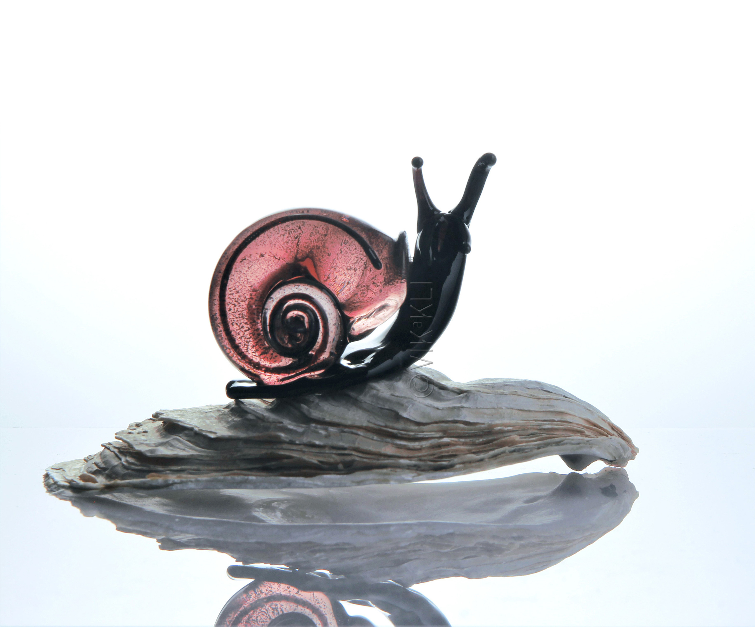 Улитка из муранского стекла на белом фоне. Предметное фото.
