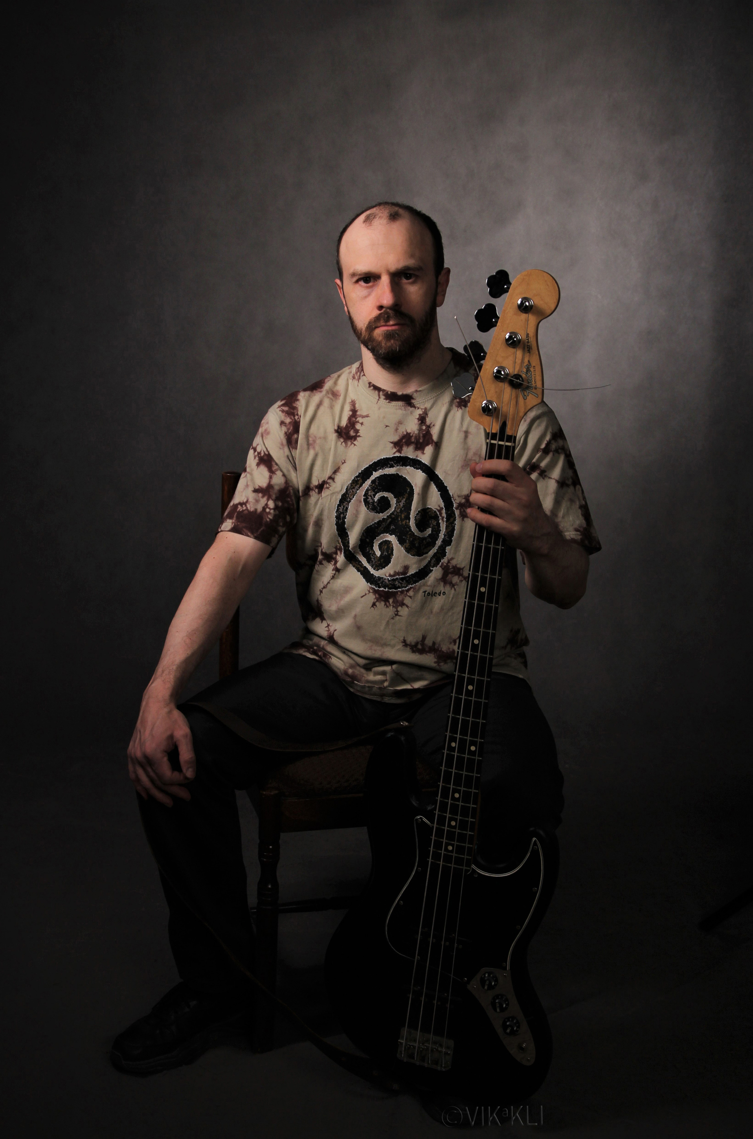 Портрет мужчины с бас-гитарой на сером фоне