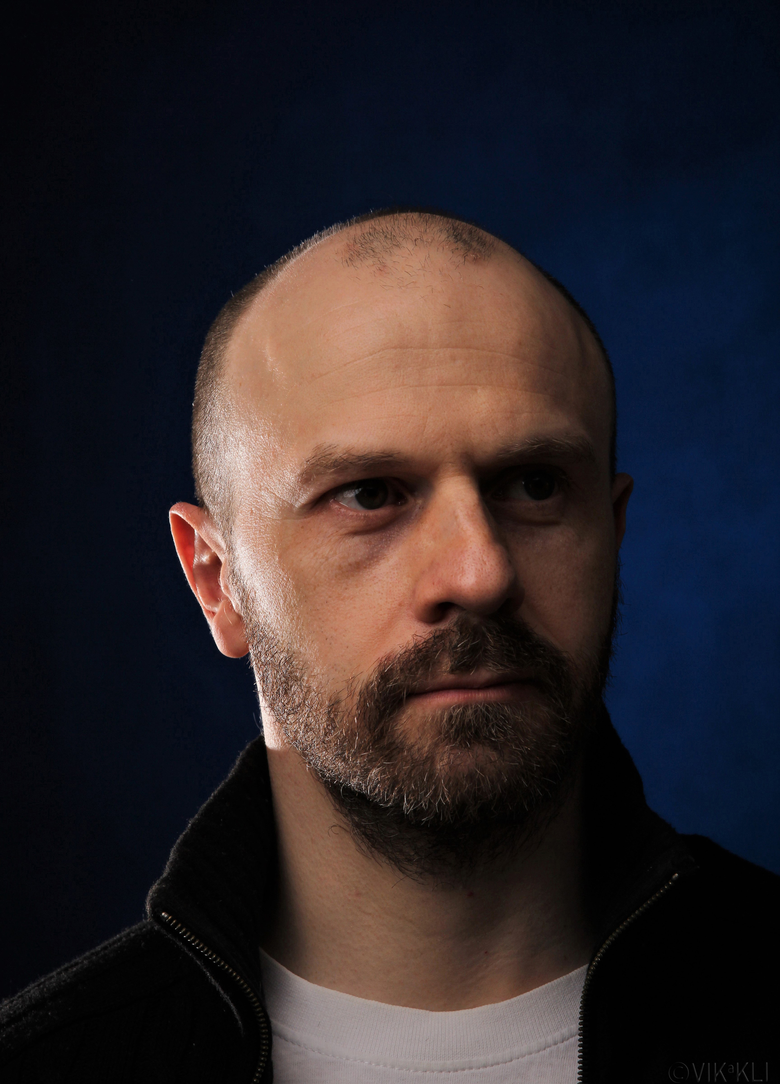 Портрет мужчины в чёрном свитере на синем фоне