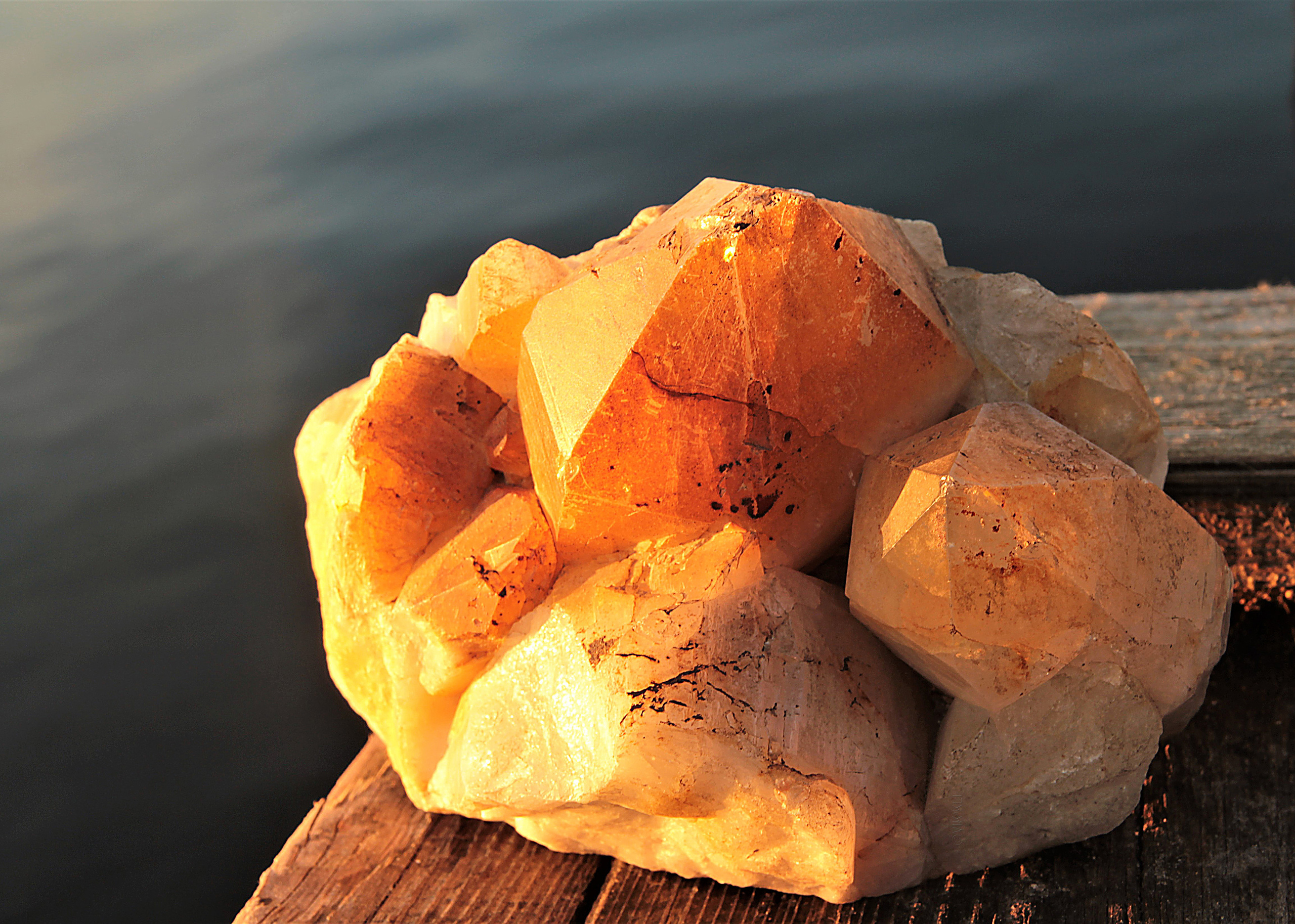 Минерал цитрин на фоне моря на закате. Художественное предметное фото.