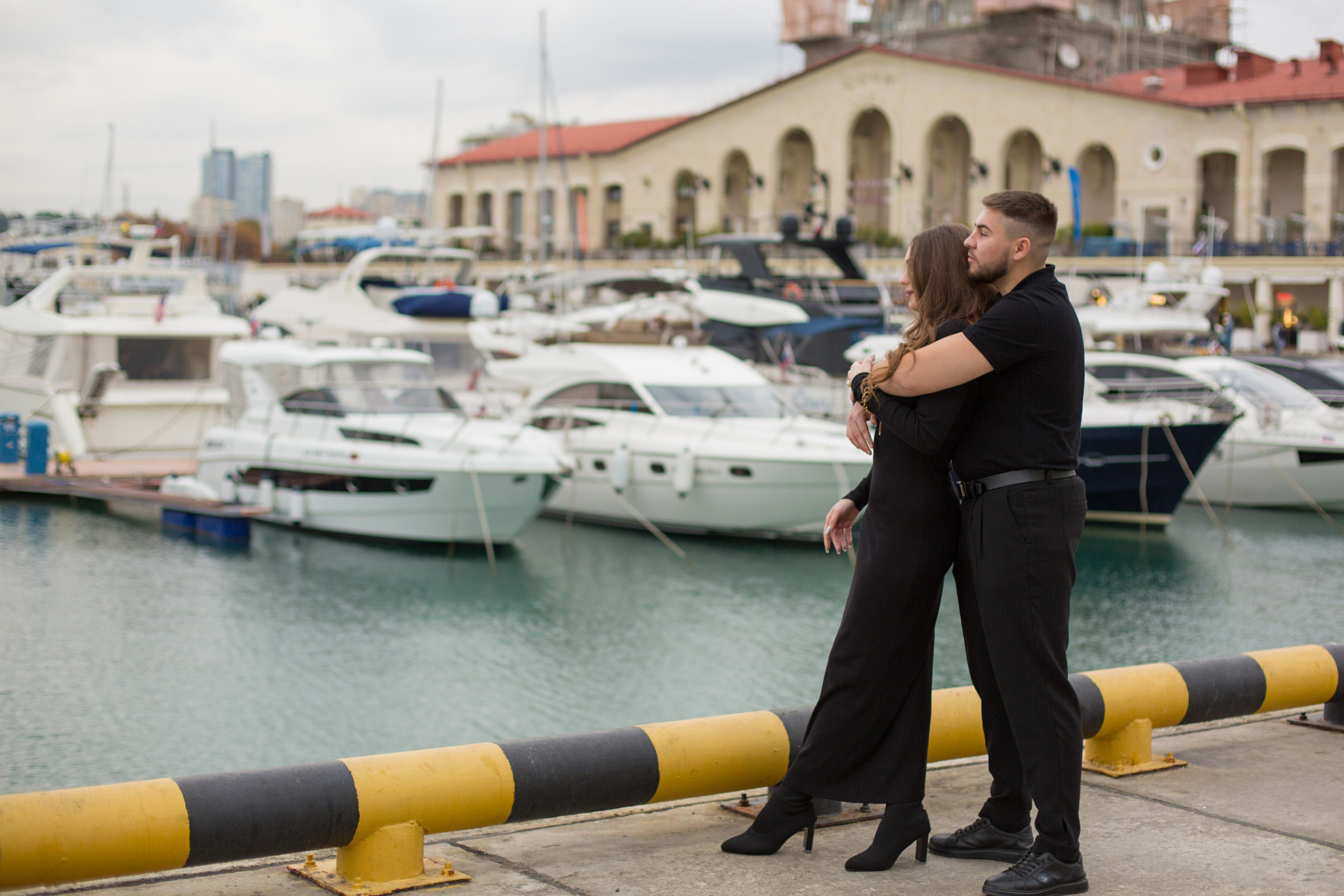 парень и девушка стоят в морском порту обнявшись