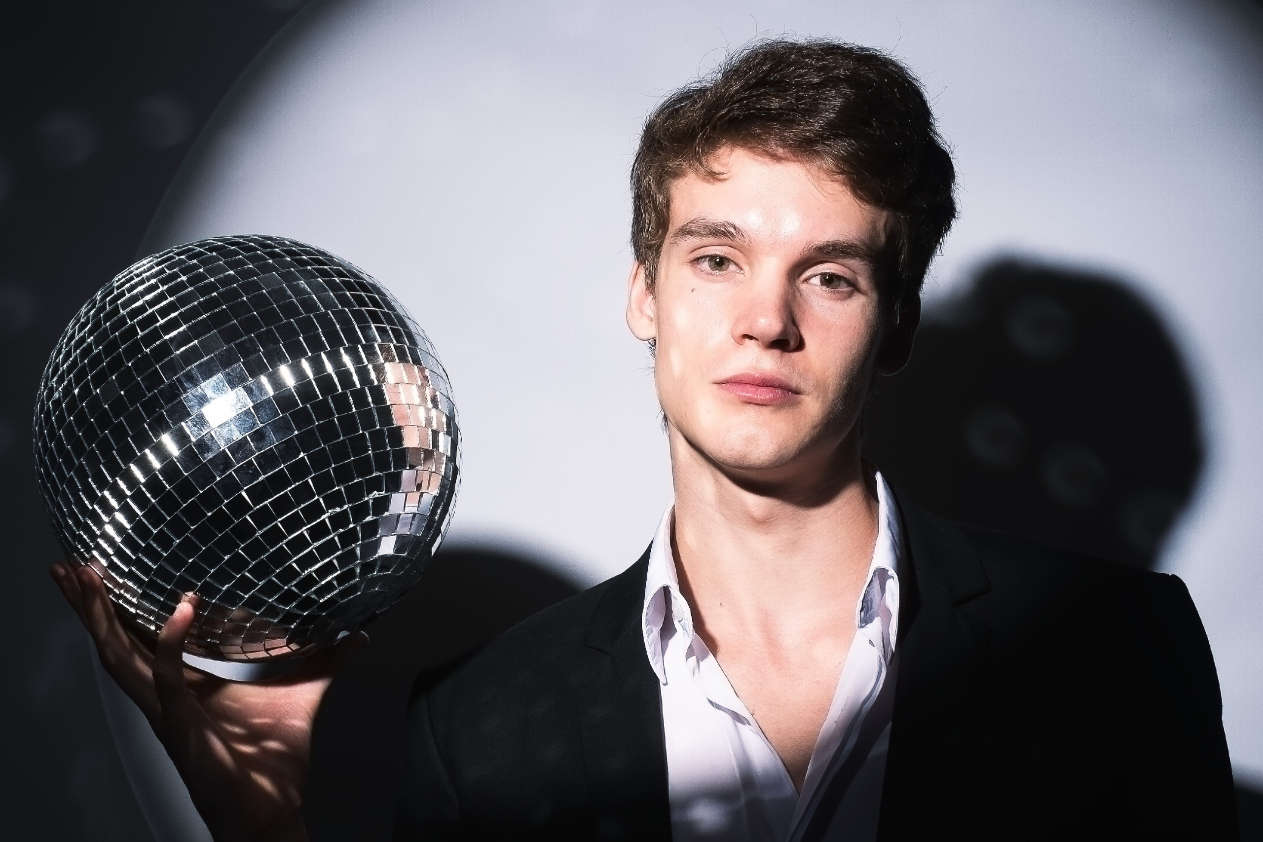 Молодой человек в костюме держит в руке диско-шар