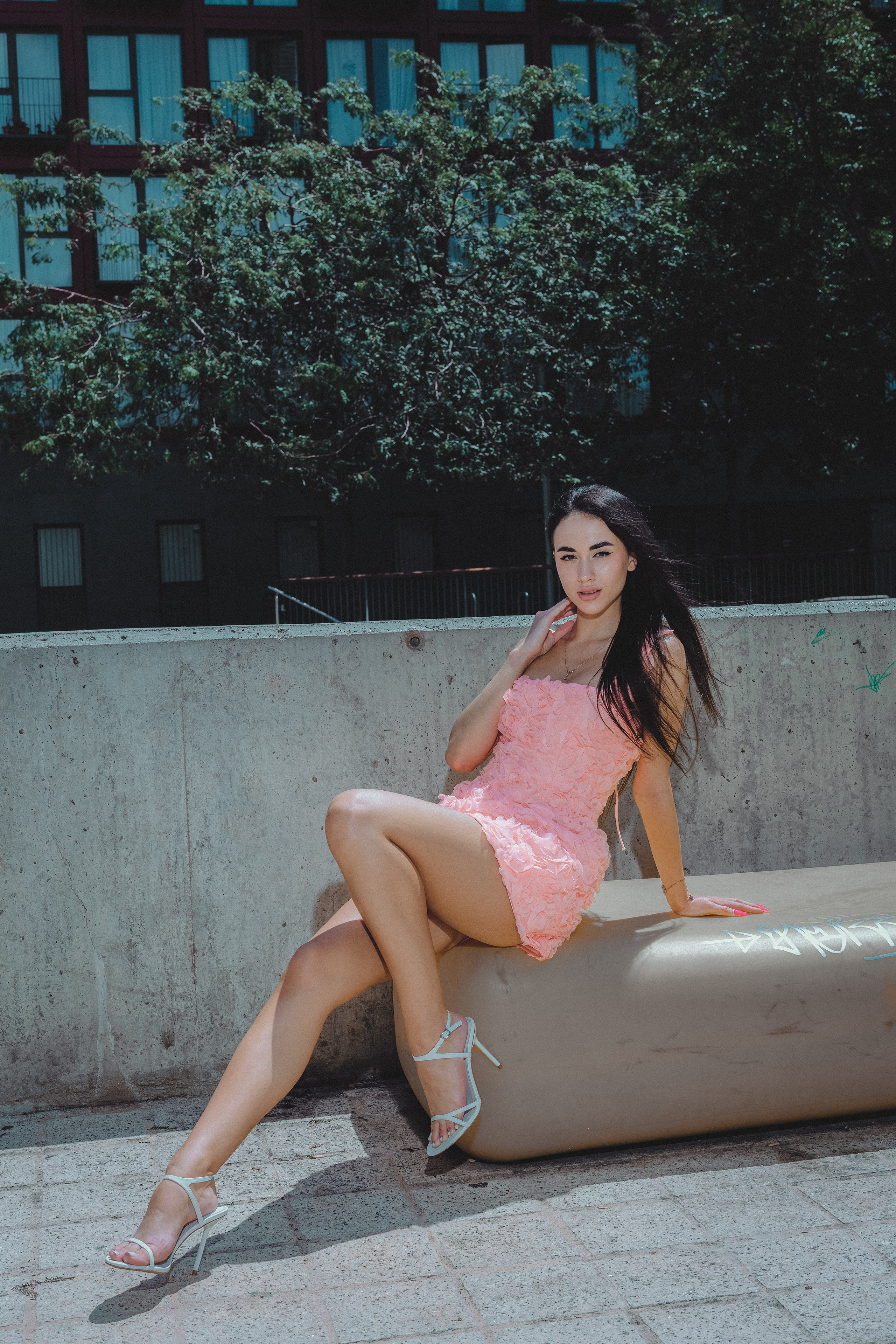 Young woman in a soft pink gown walking through a narrow Barcelona alley.