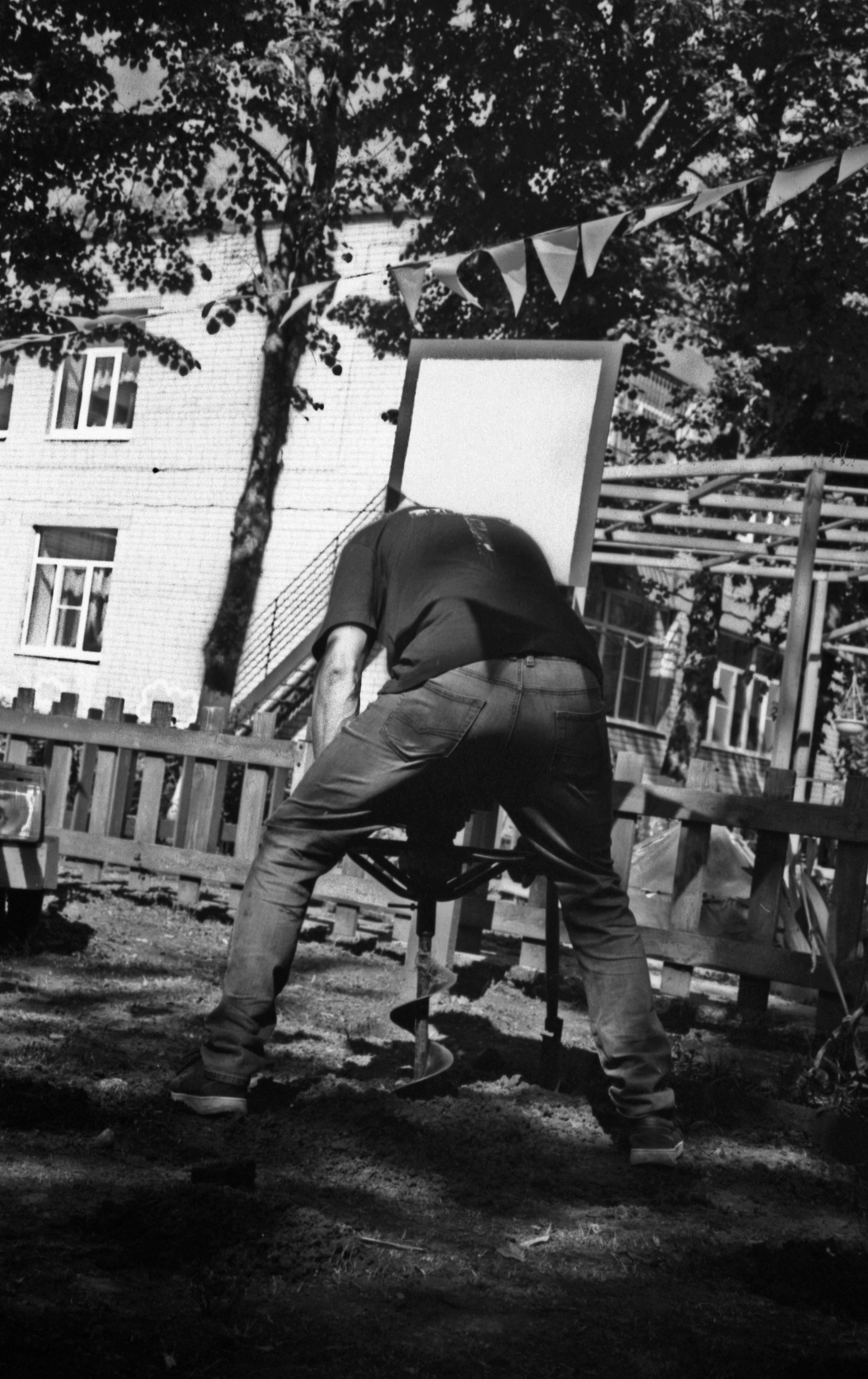 Серёга бурит грунт во дворе. Жесткая геометрия труда, контрастные тени и флажки над головой.
