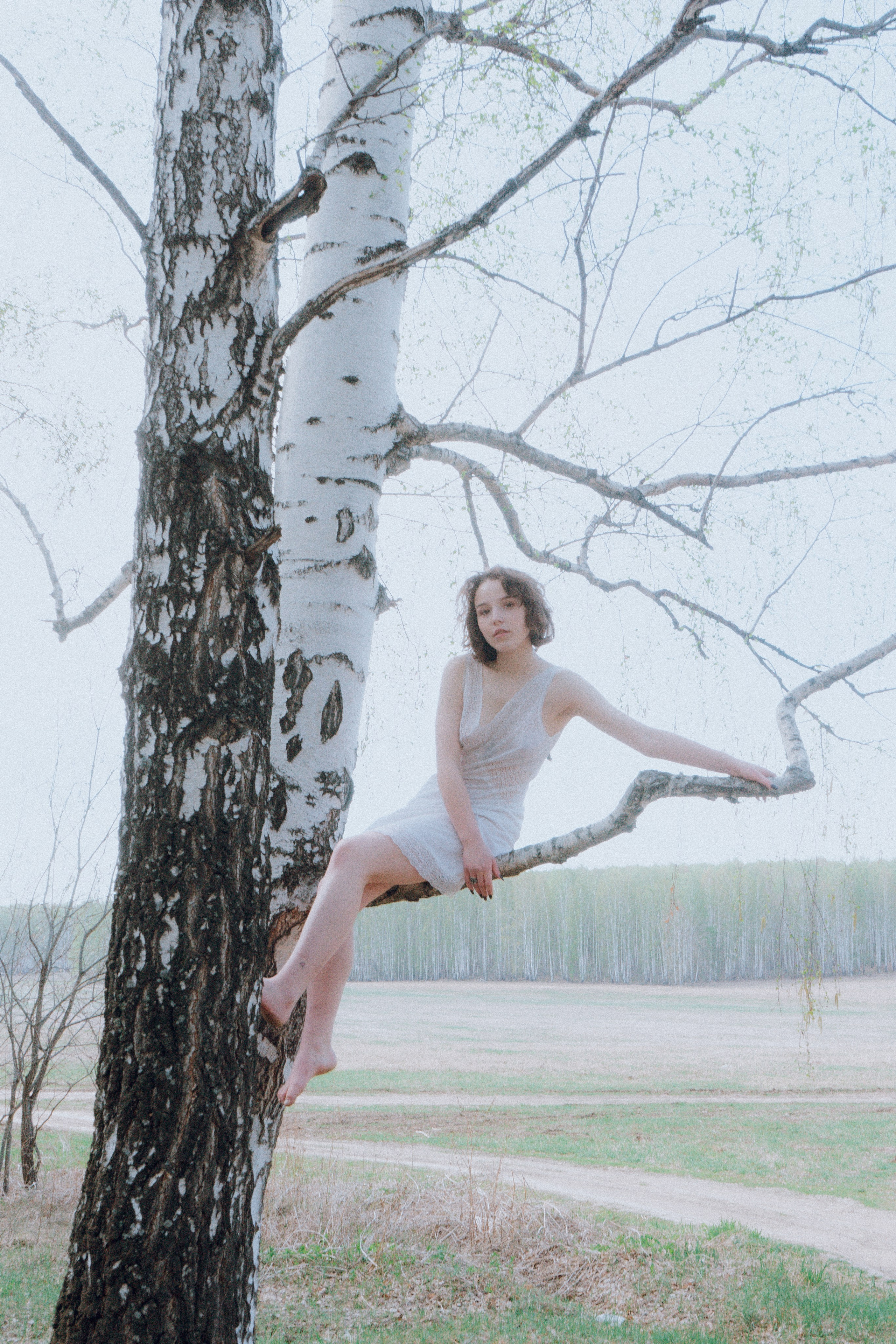 Модель в белом платье на дереве