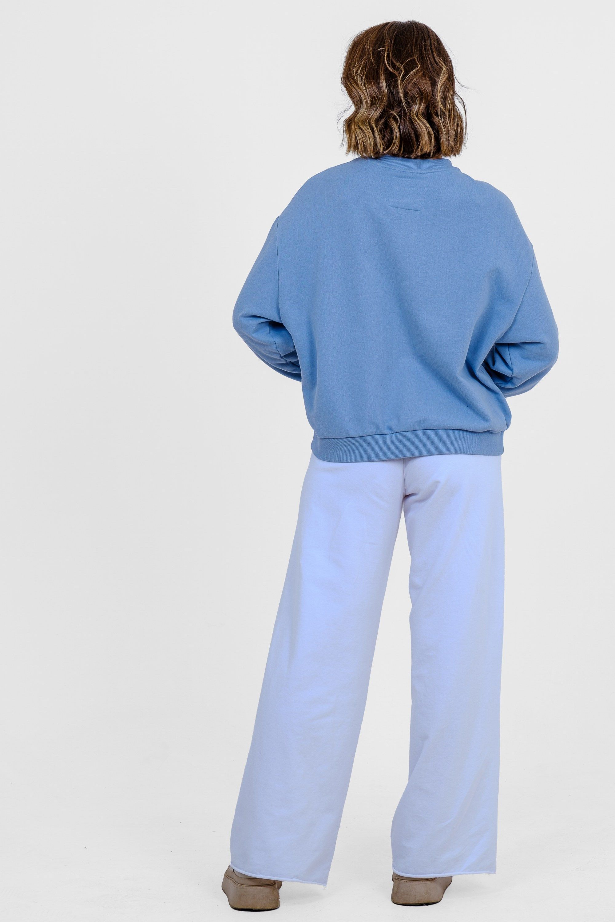 Девушка в голубом свитшоте, голубых спортивных брюках и белых кроссовках. Вид со спины. Фото для маркетплейсов