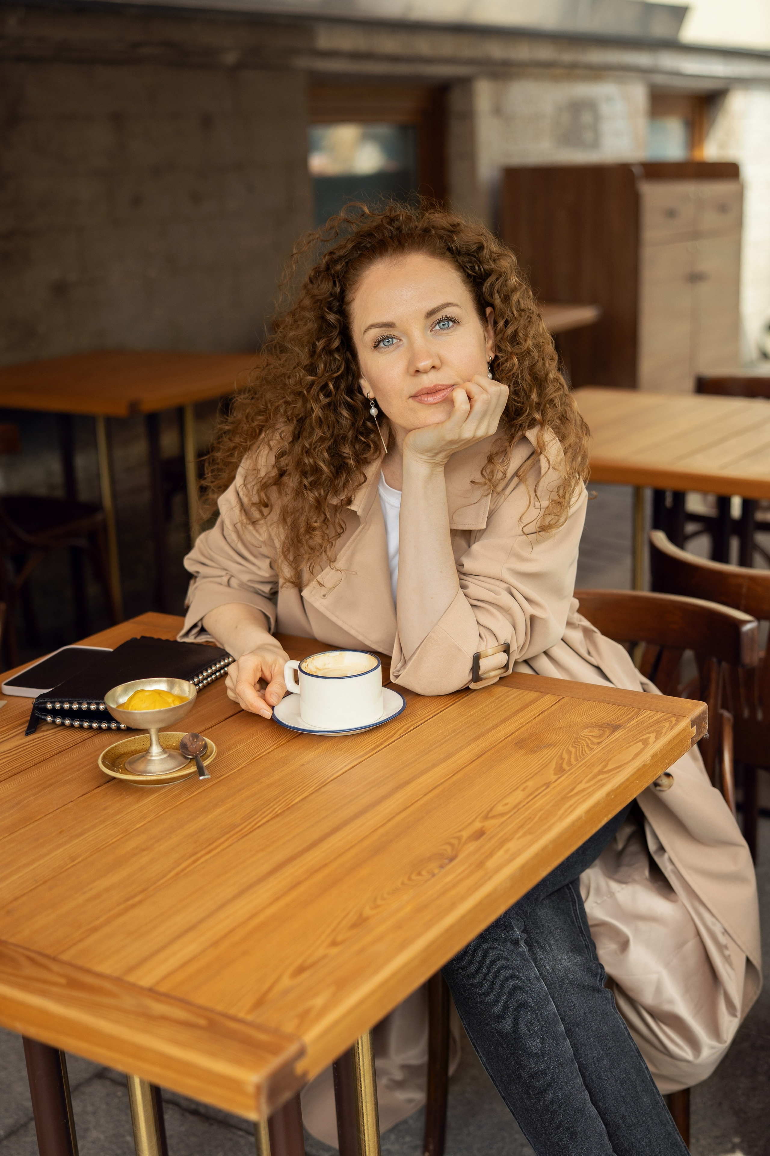 Женщина пьет кофе в уличном кафе.