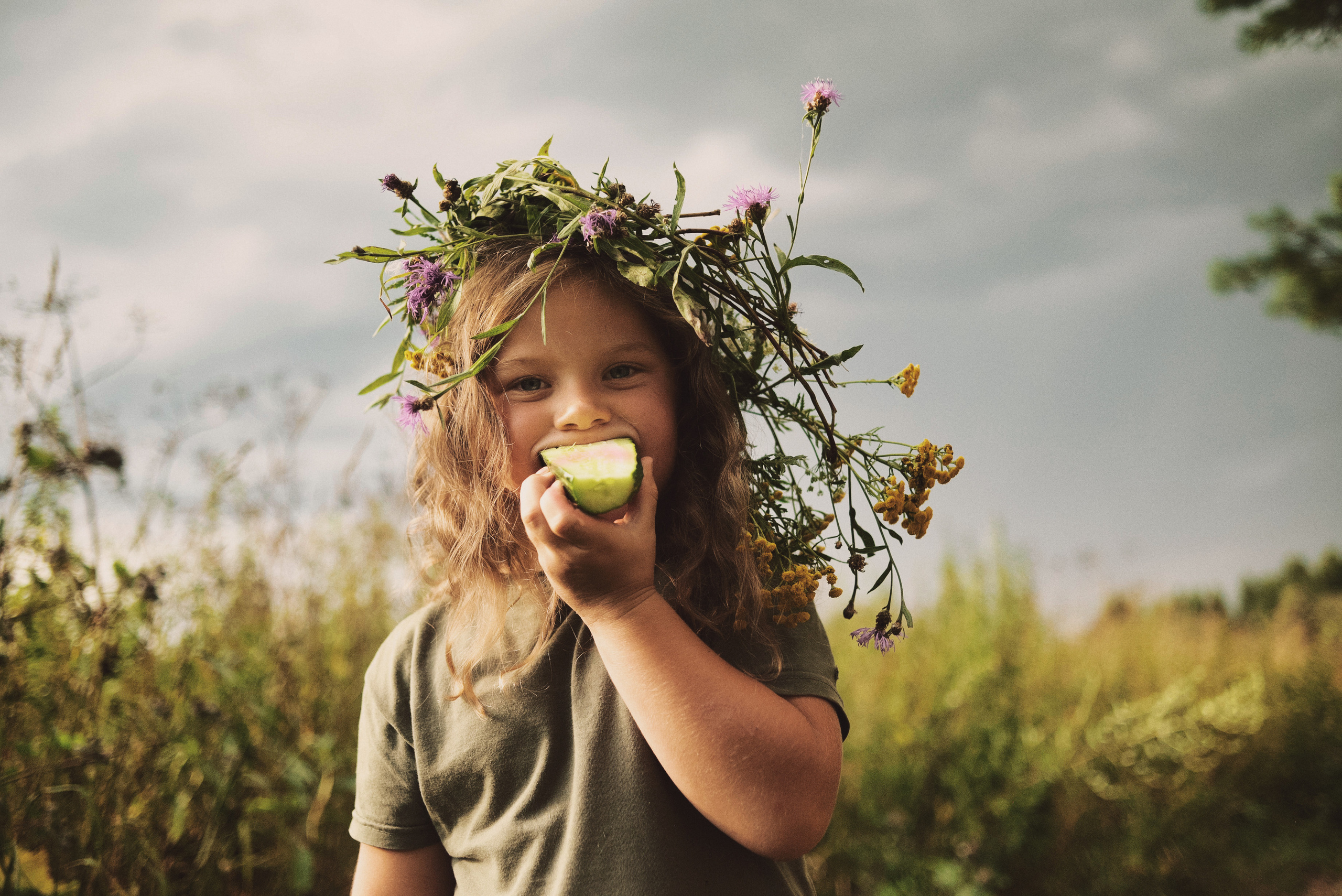 Девочка кушает яблоко летом в поле