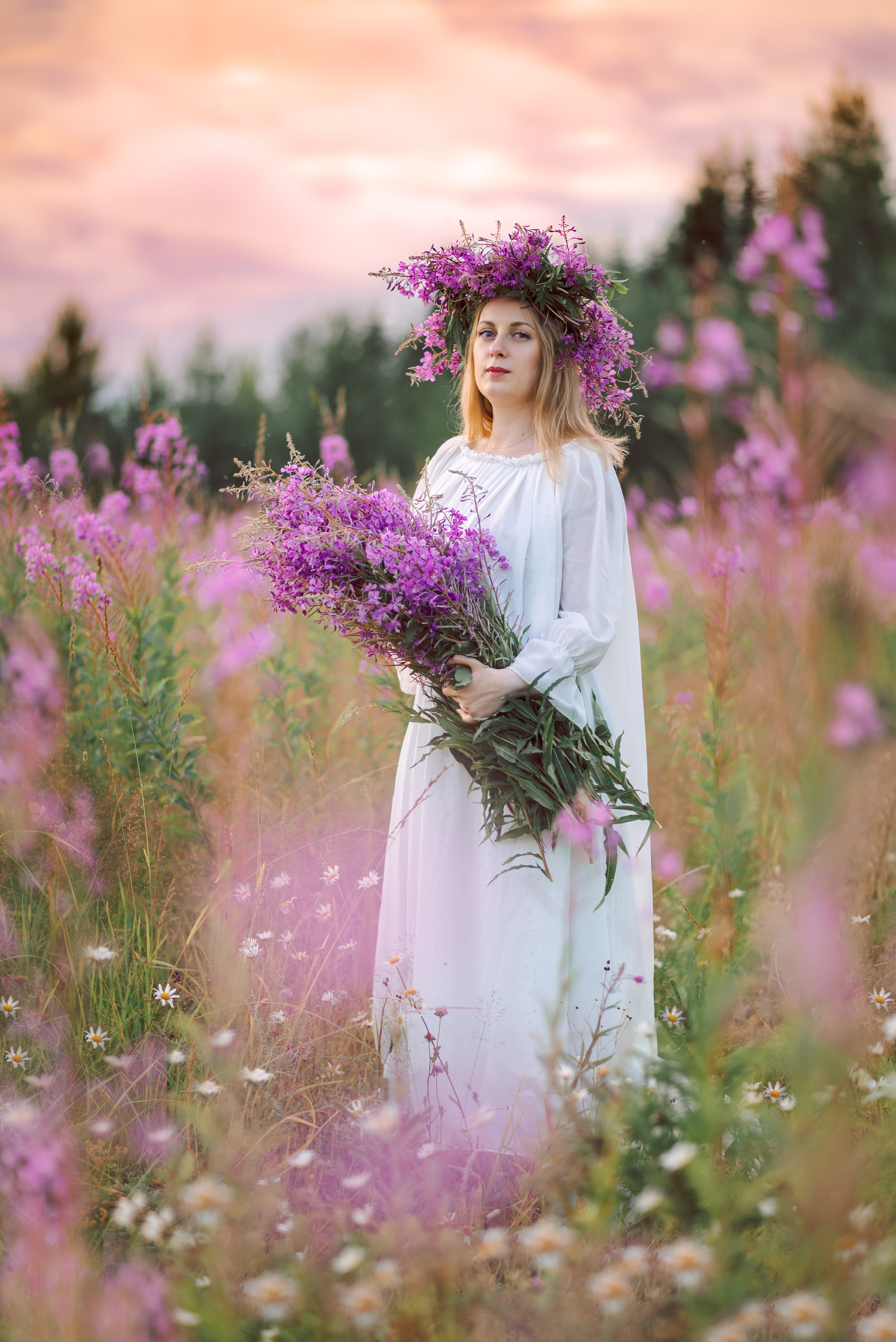 Девушка на закате в поле иван-чай в руке большая охапка розовых цветов, на голове венок из иван-чая