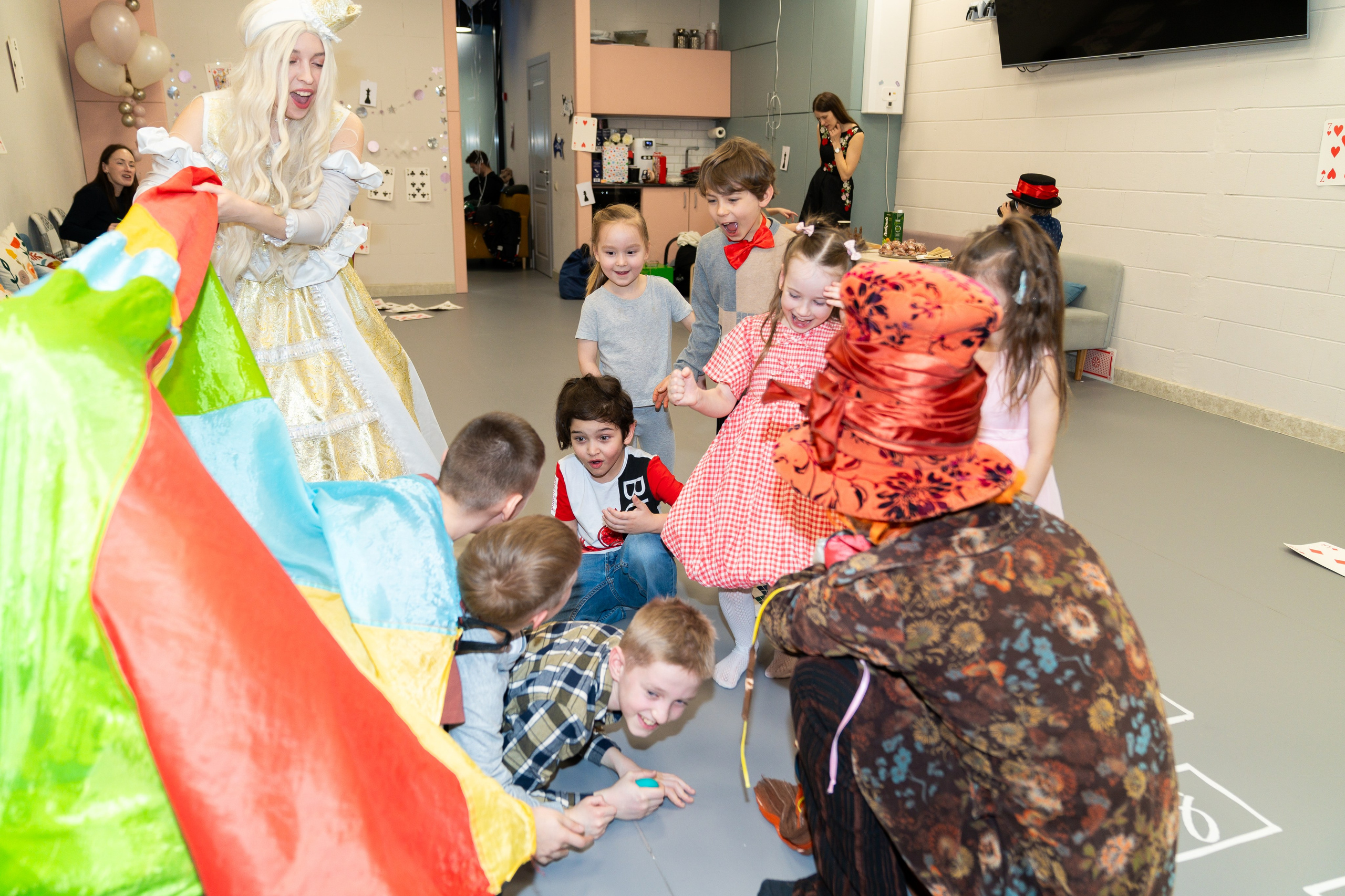 Группа детей и аниматоры Белая Королева с Шляпником играют с радужным парашютом на празднике Алиса в стране чудес, фото Евгений Мальцев.