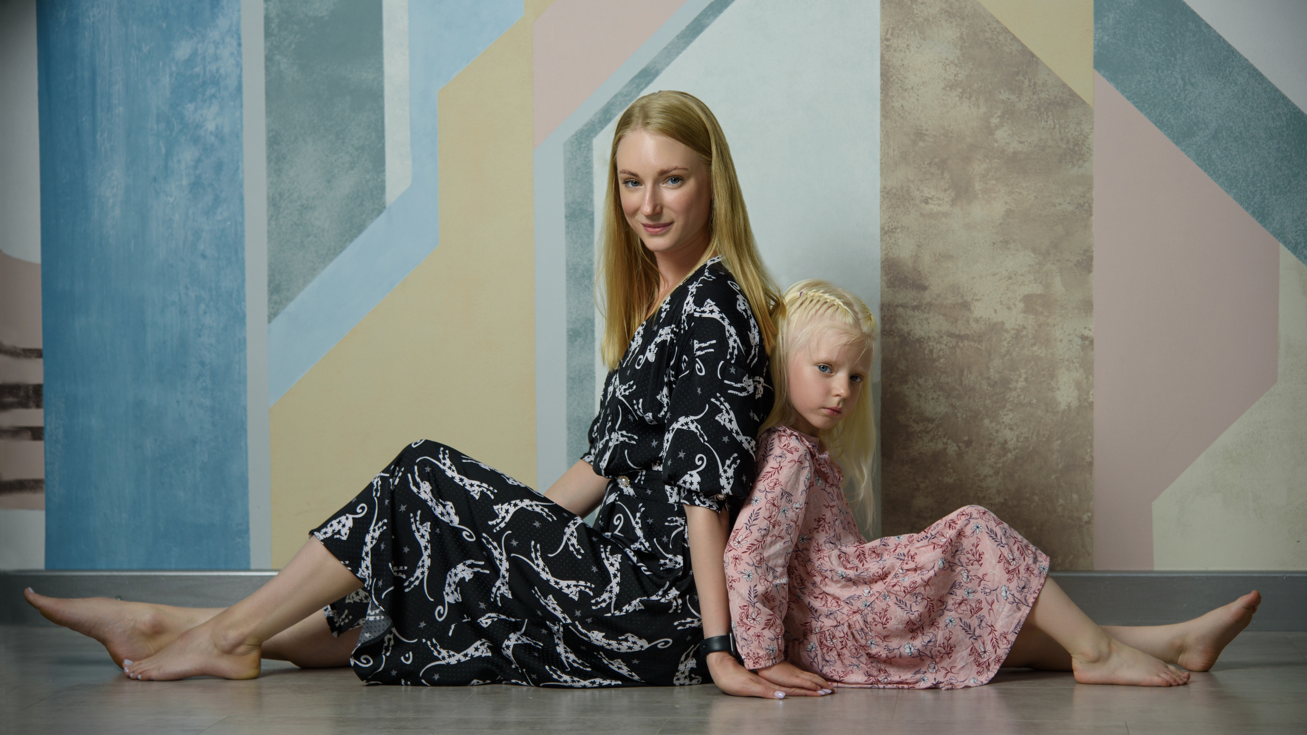 мама с дочкой сидят на полу спиной друг к другу