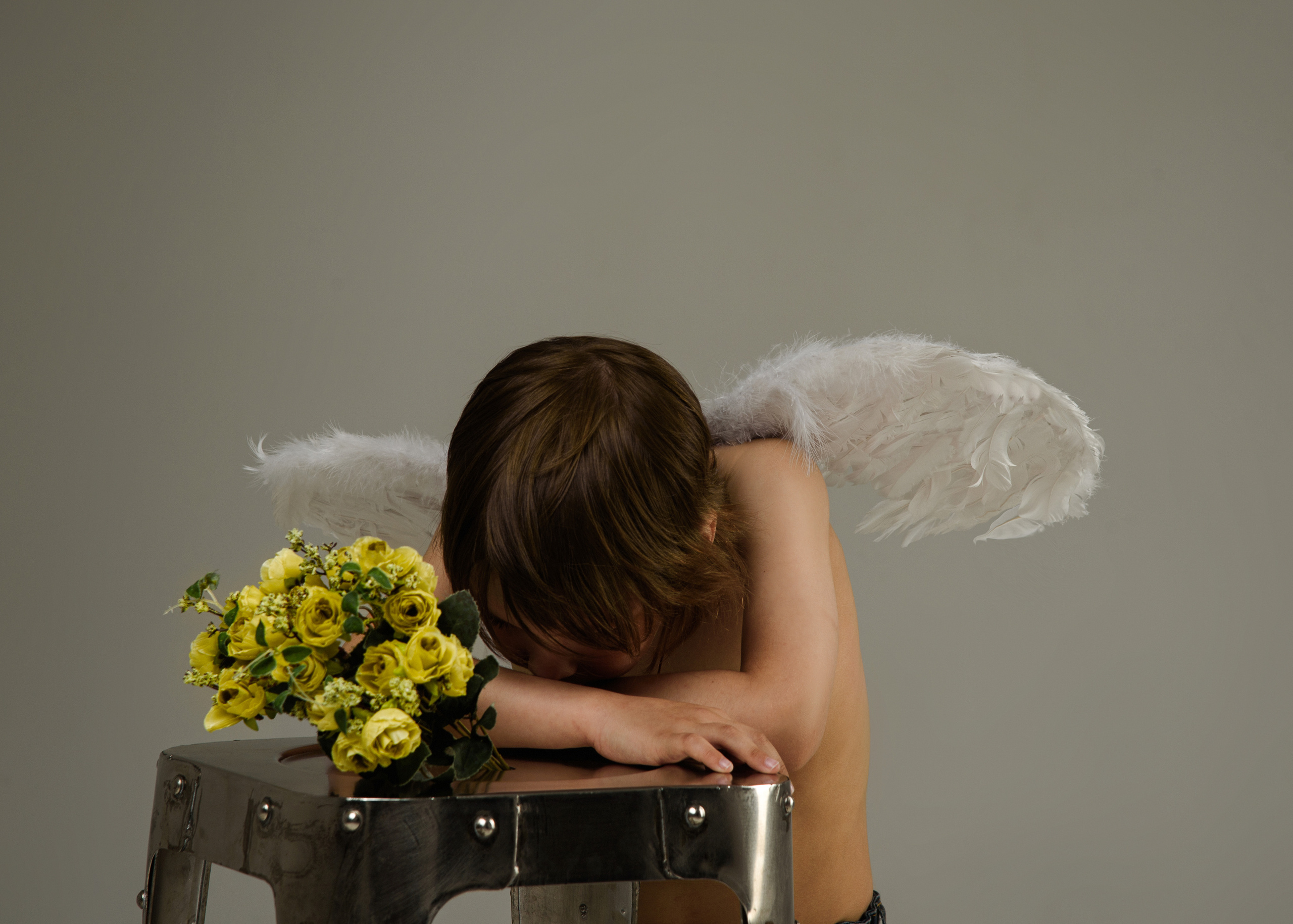 мальчик ангел спрятал лицо грустит рядом лежит букет цветов