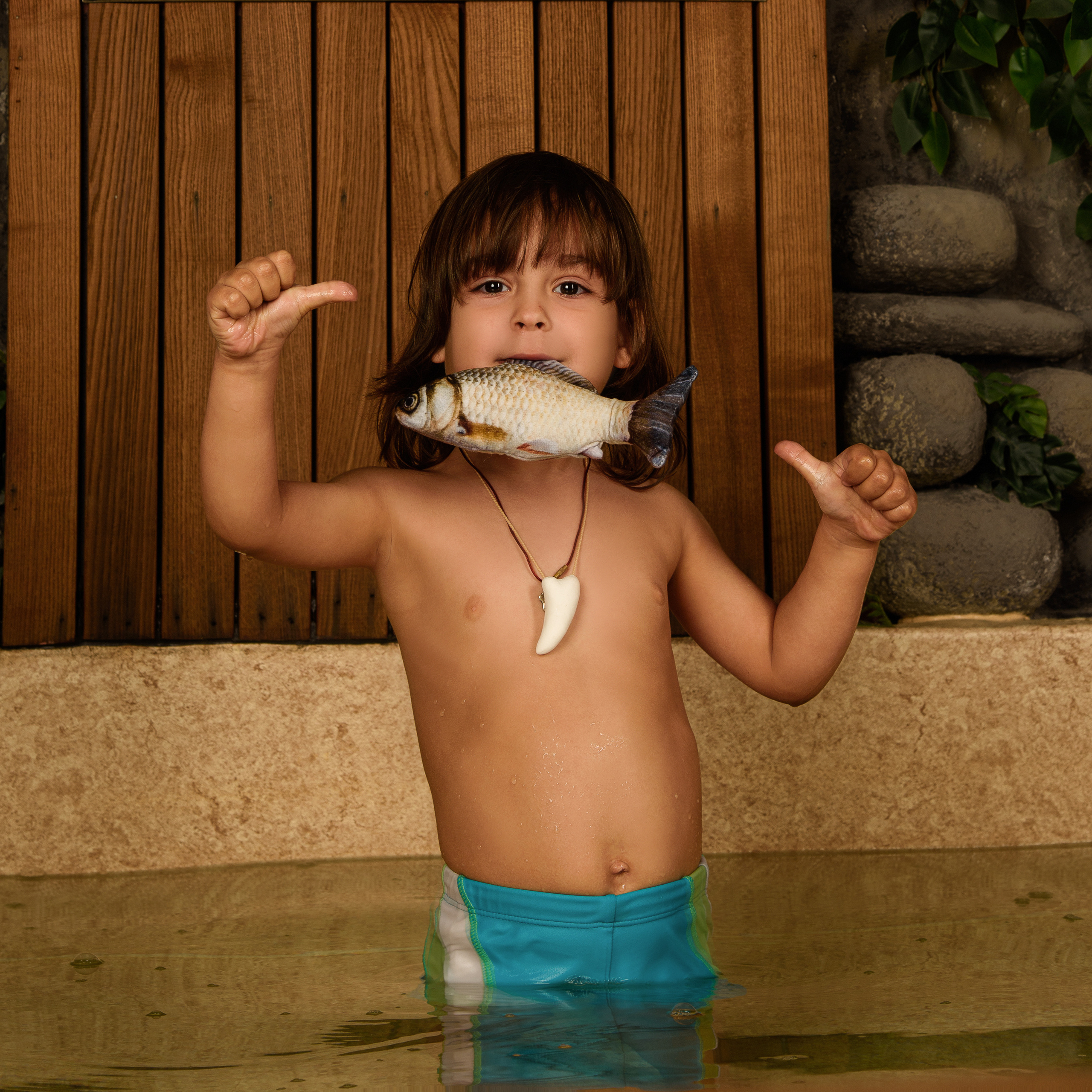 Маугли в воде с рыбой в зубах