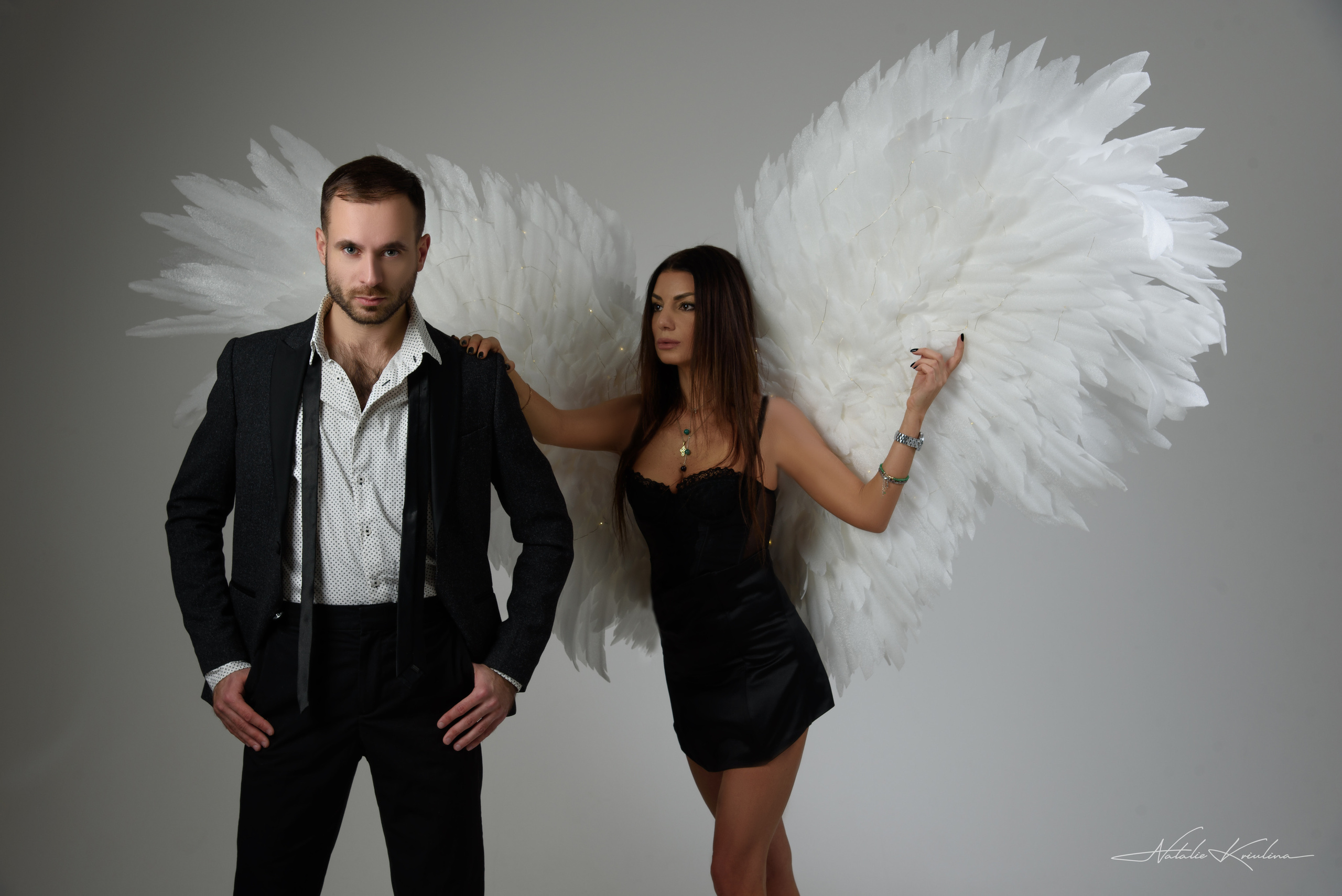 семейная фотосессия парень в деловом костюме за спиной которого стоит девушка ангел 