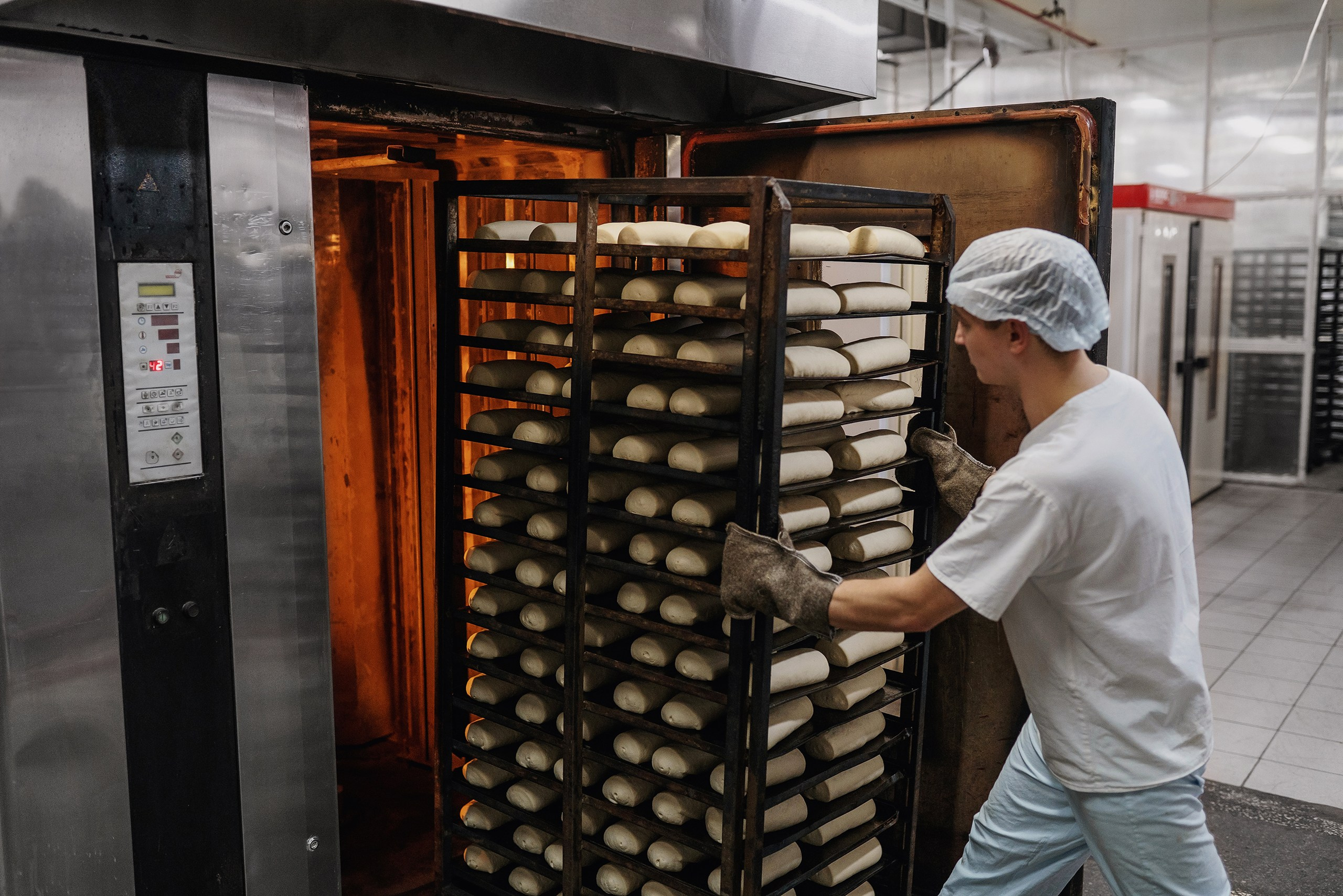 работник загружает хлеб в печь