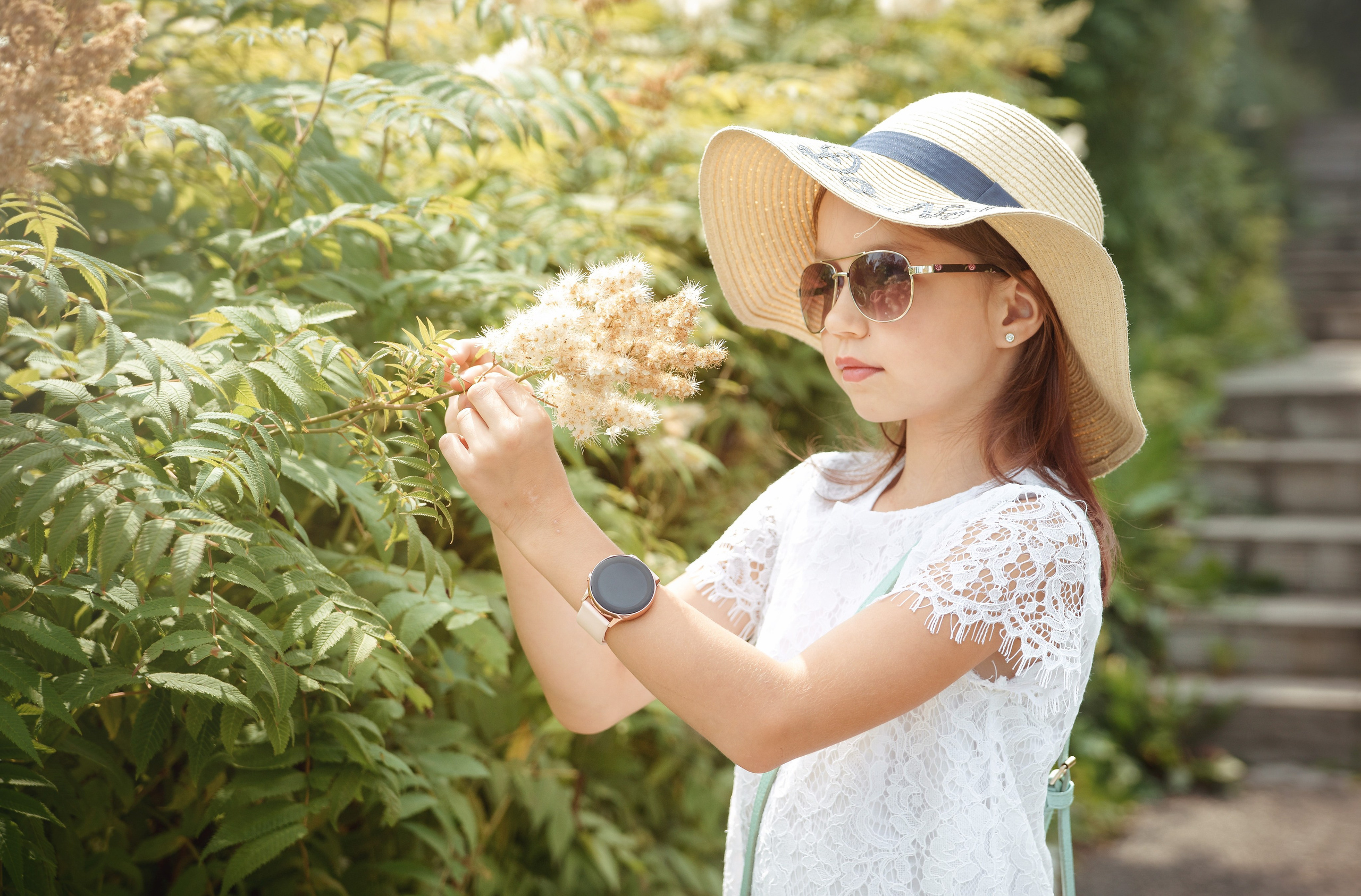 Детская фотосессия летом - девочка стоя смотрит на цветы