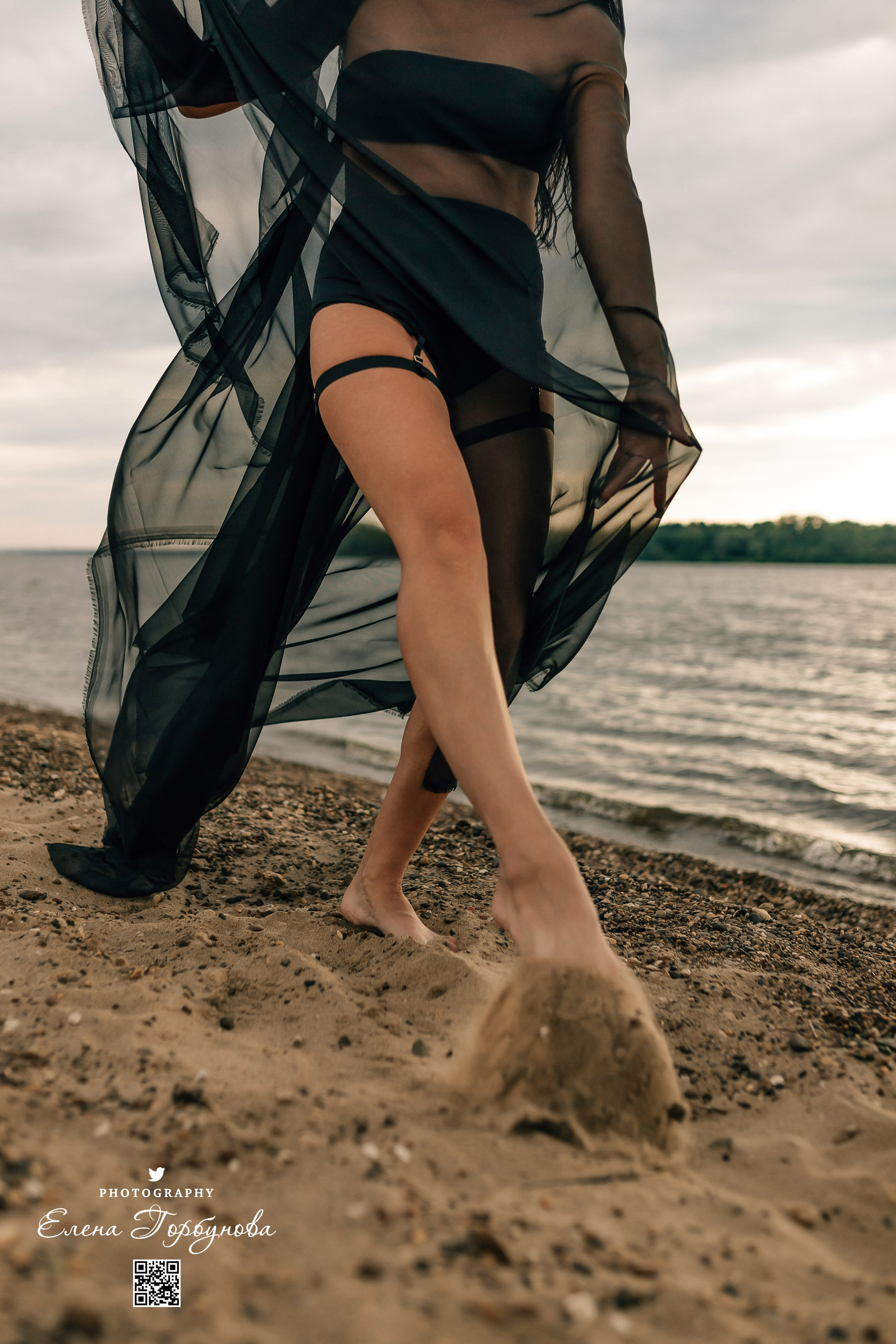 Фотосессия с черной тканью. Легкая черная вуаль летит на вертру. Фотосессия у реки черная серия с тканью. Девушка укуталась в черную ткань. Прогулка по набережной. Песок, речка, модель в черном. Качели над водой, Закат. Девушка лежит на песке. В зеленых деревьях