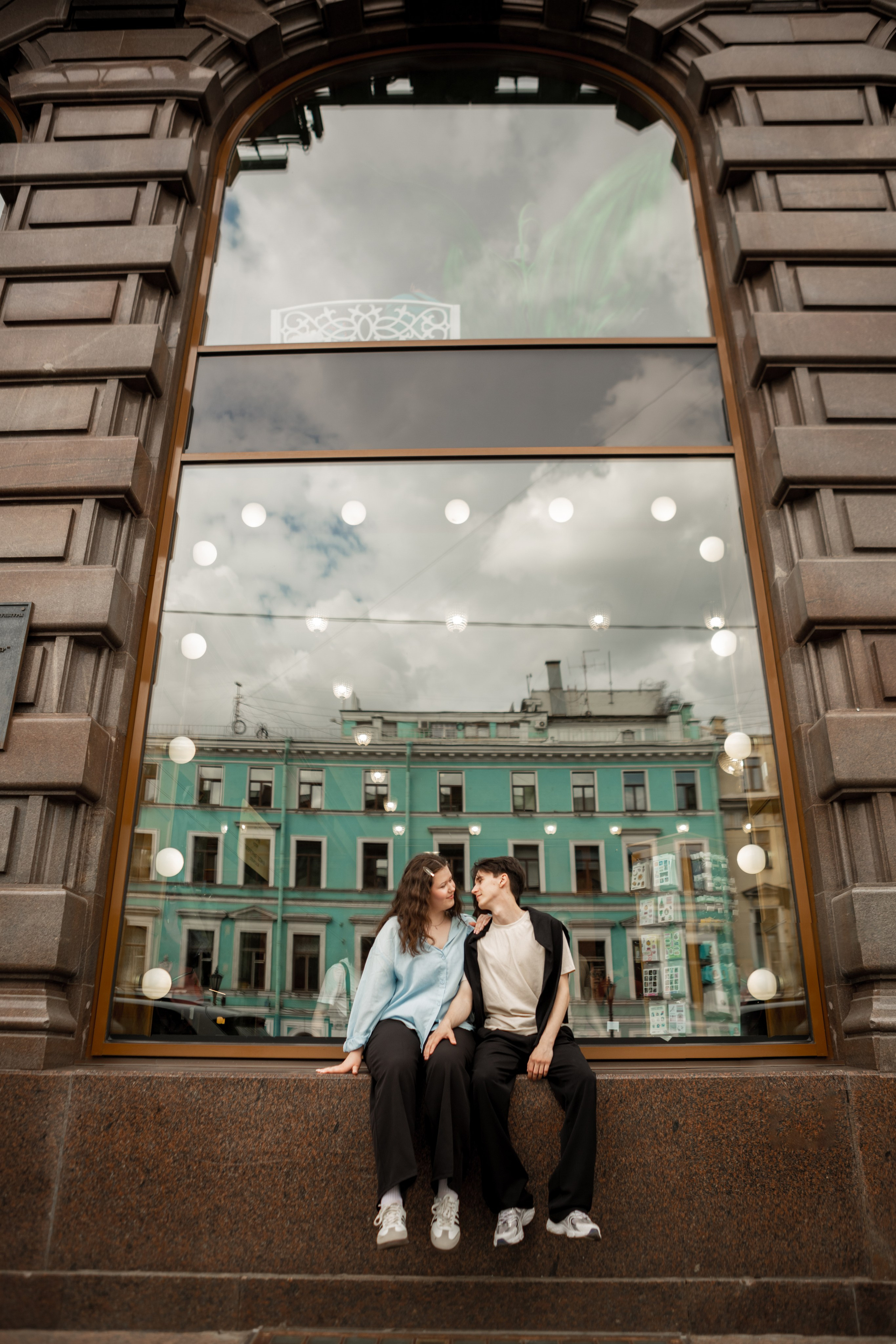 Влюбленная пара на фотопрогулке лавстори у окна с красивым отражением.
