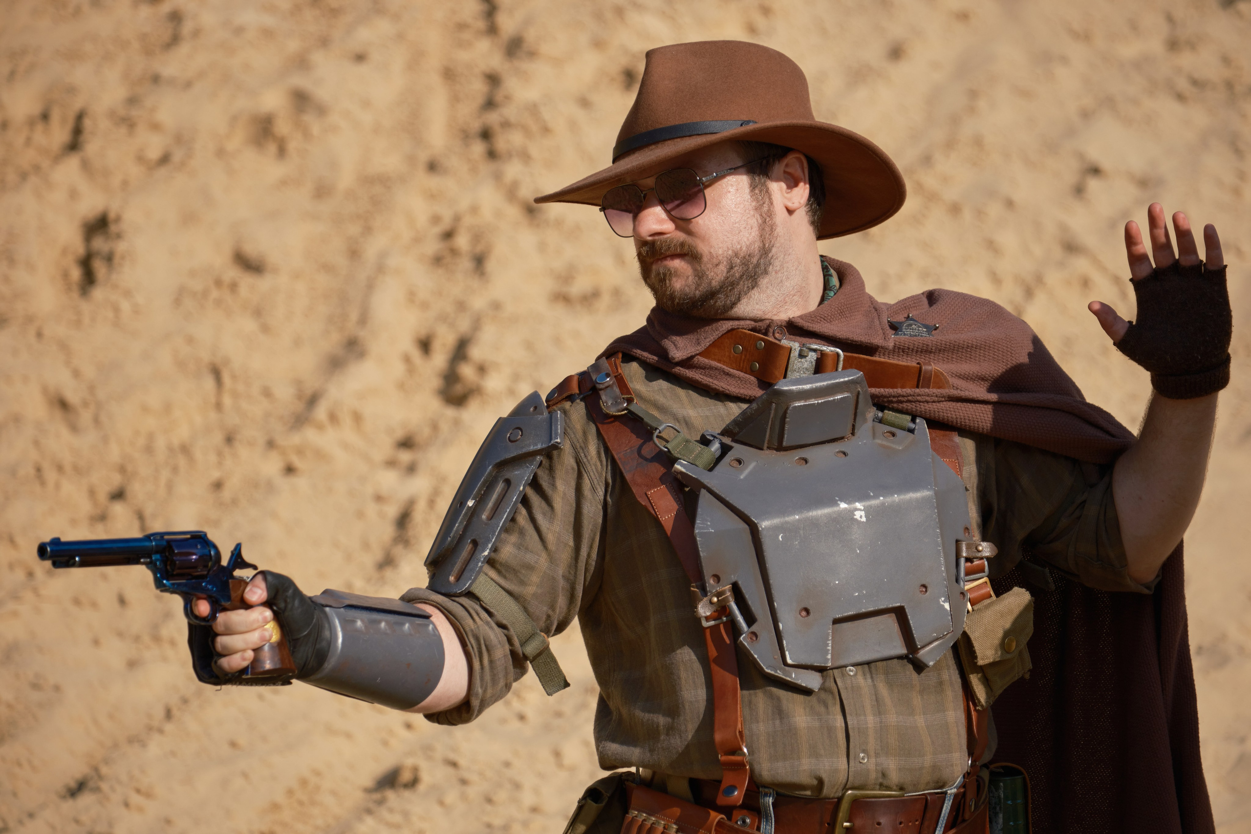 Мужчина в ковбойской шляпе и очках целиться из револьвера в стиле пост апокалипсис