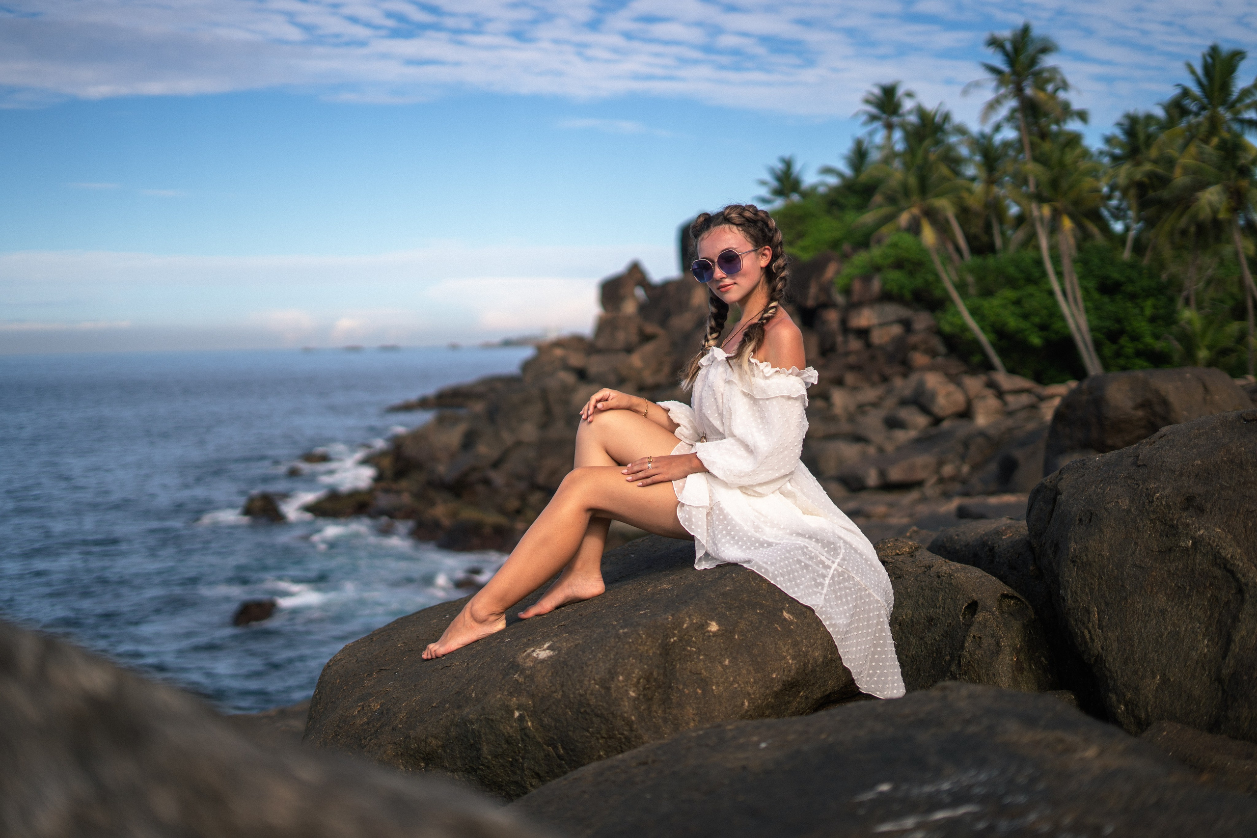 a girl in a white dress and glasses against the blue sky and ocean