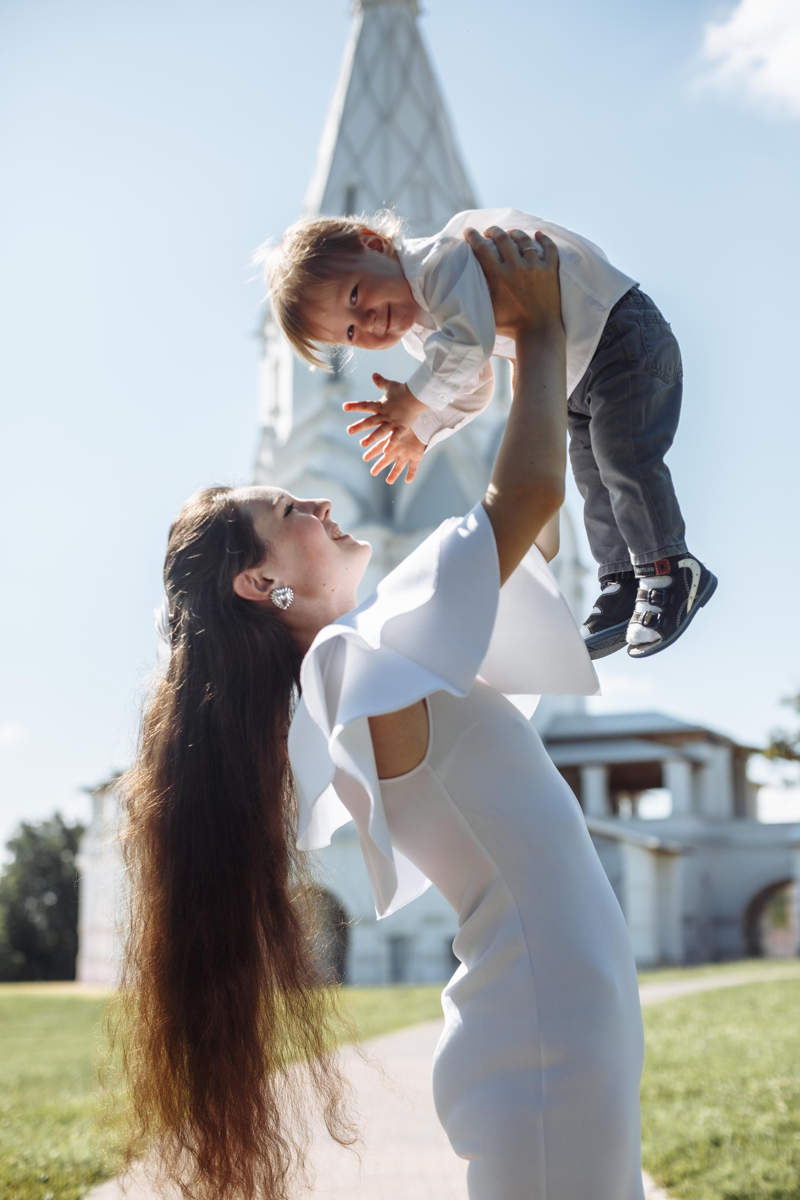 Фотограф на красивую семейную фотосессию, в кадре мама с поднятым над головой малышом в парке Коломенское
