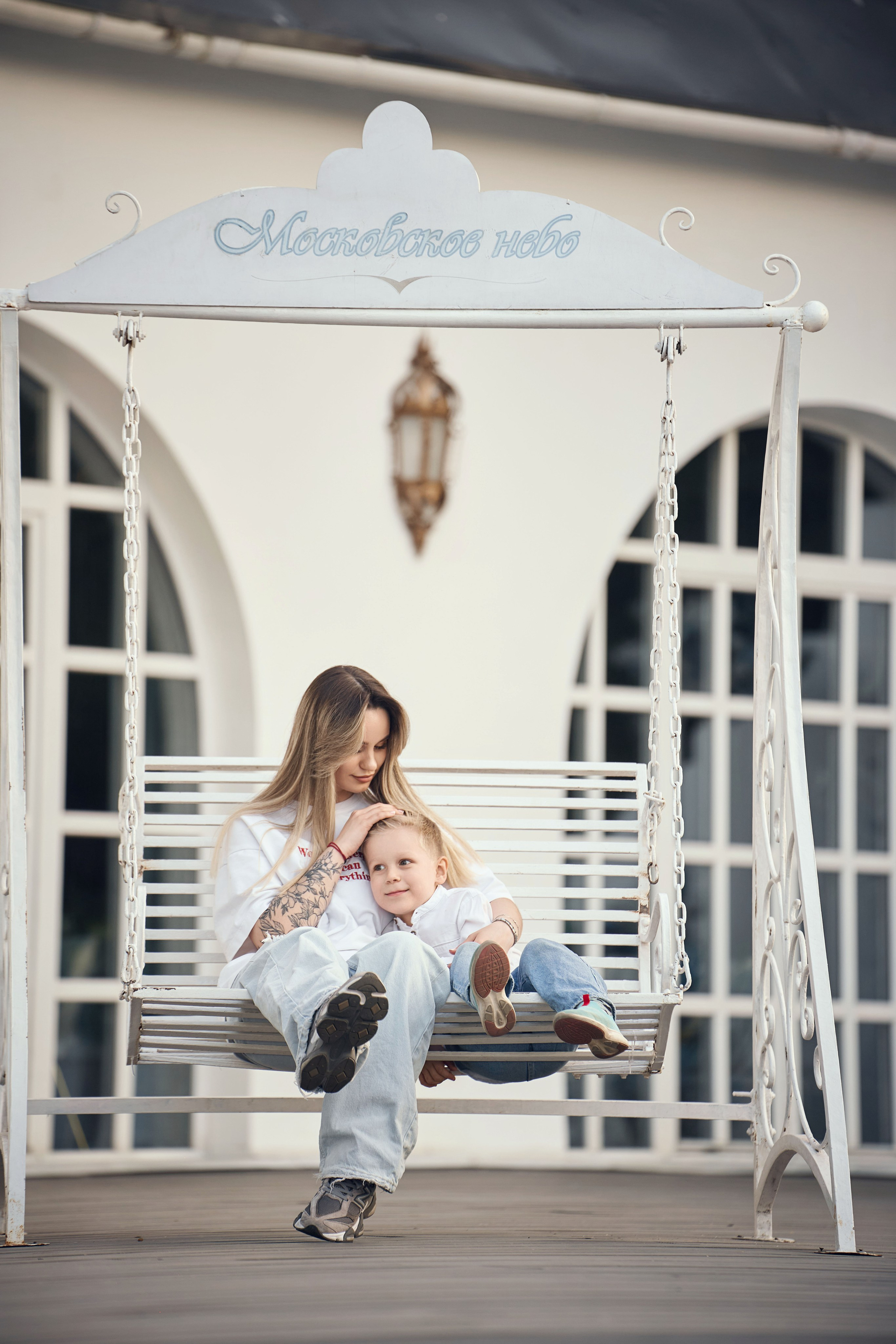 мама и сын сидят на лавочке качелях у ресторана на территории ВДНХ