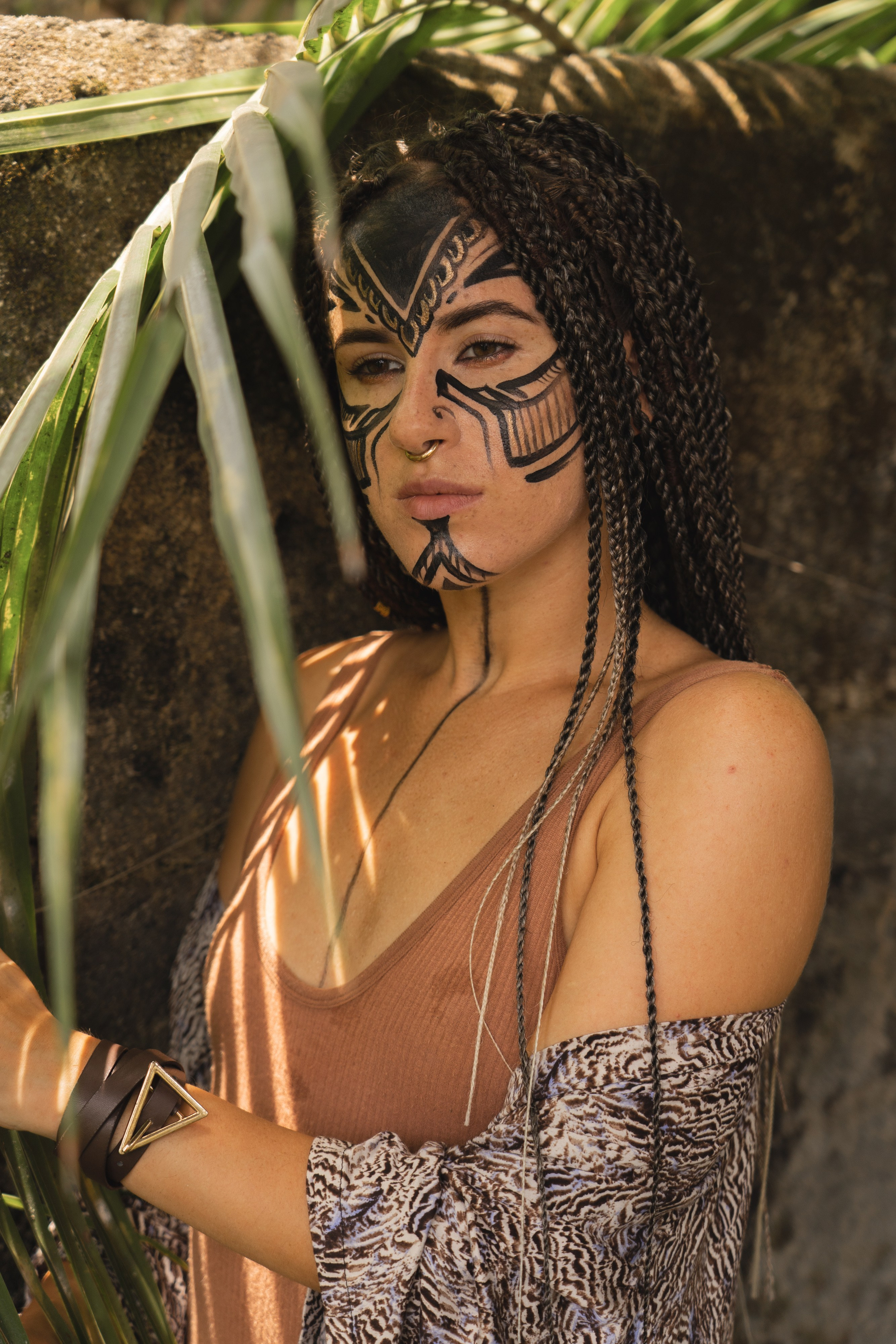 a girl with braids and painted face standing in the jungle