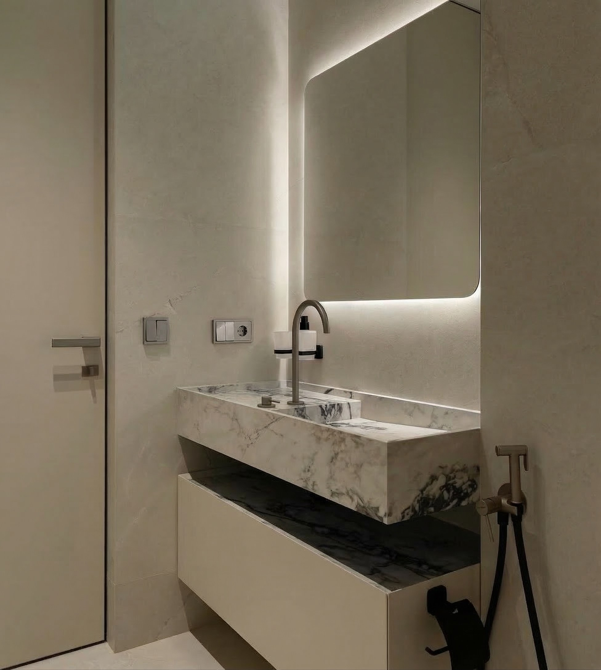 Интерьер гостевого санузла в ЖК ONYX Deluxe: раковина из белого мрамора, высокое зеркало с подсветкой по периметру и дверь скрытого монтажа. Дизайн Валерии Котович.