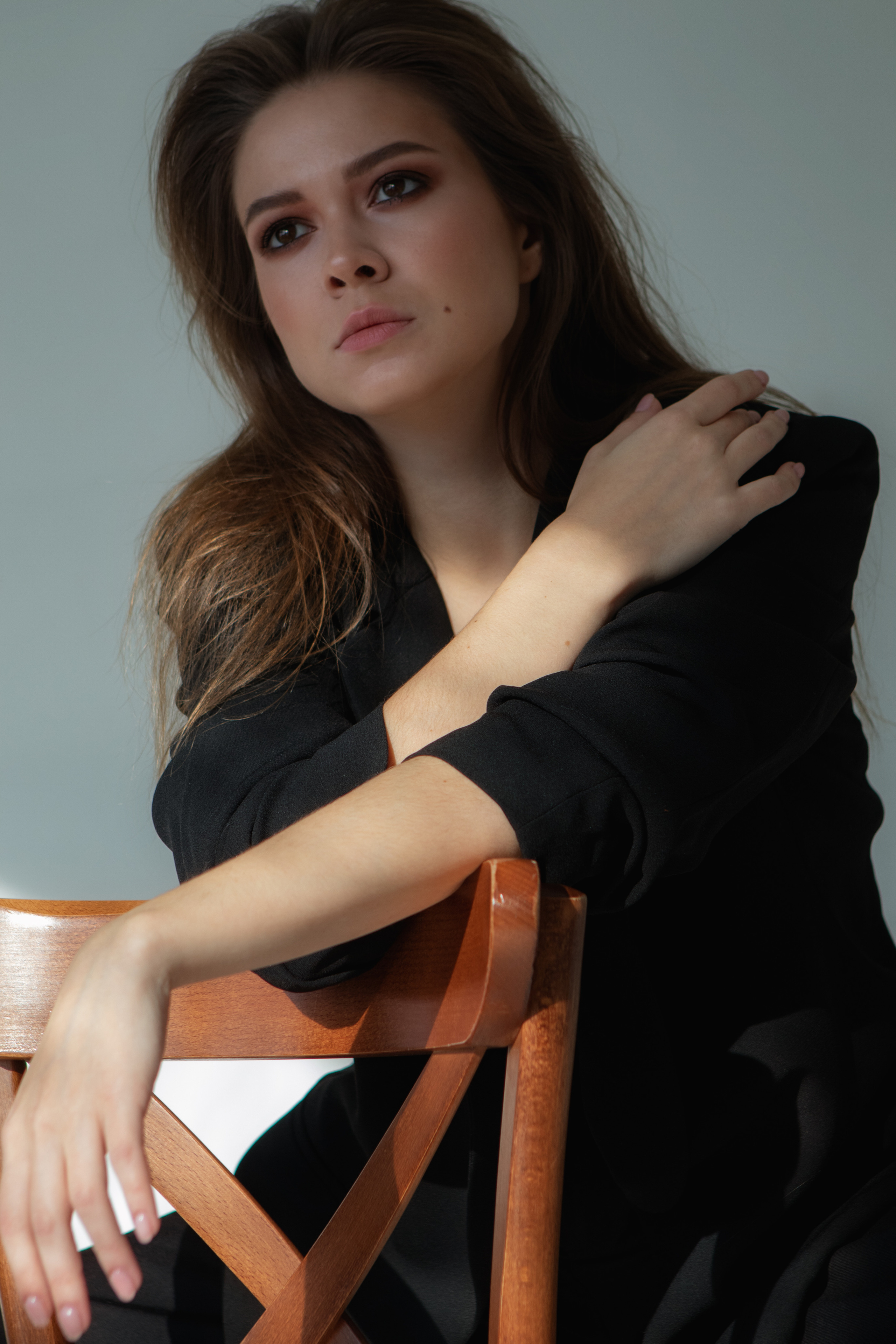 Девушка в черном со стулом в фотостудии