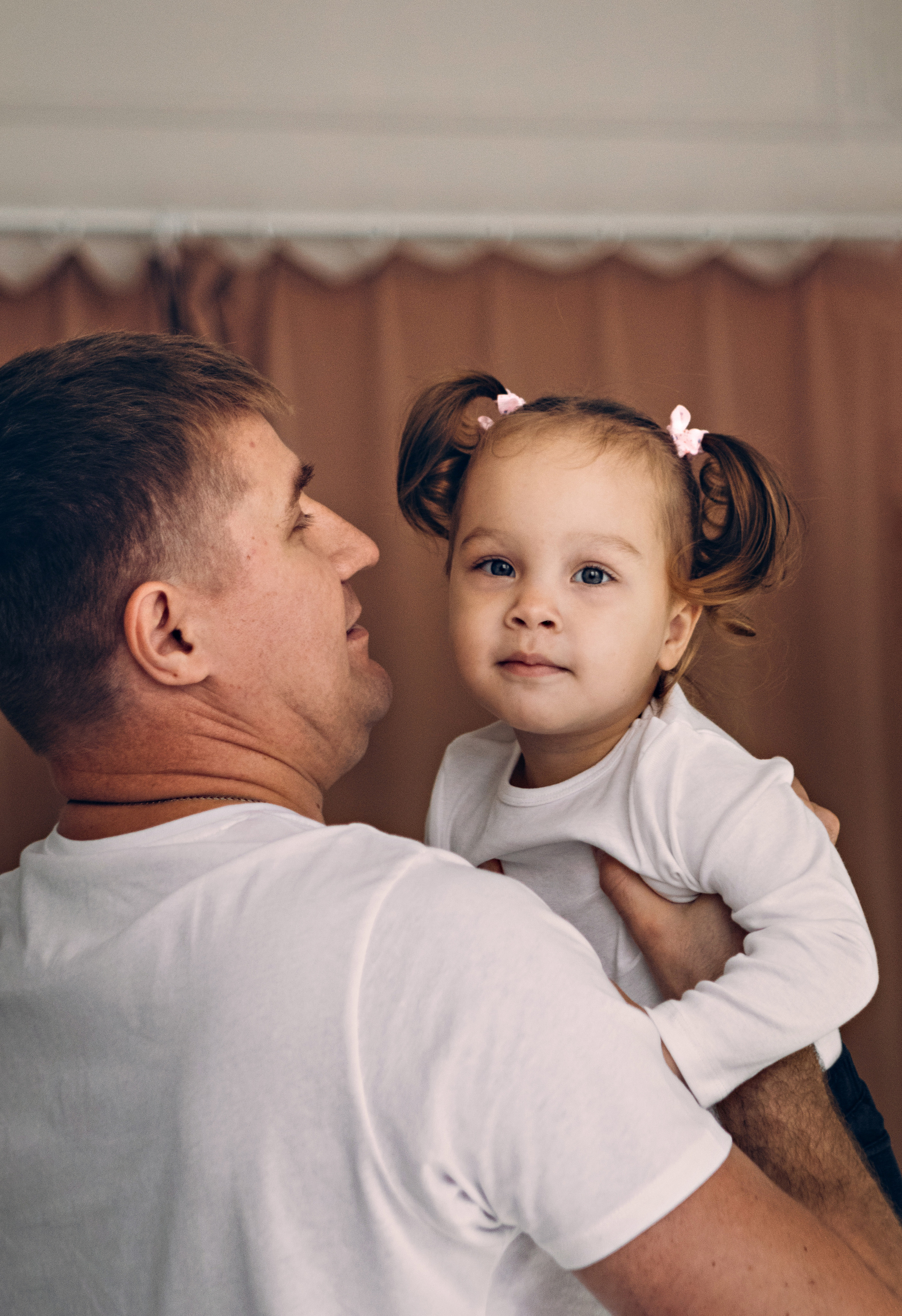 Папа держит на руках  маленькую дочку. 