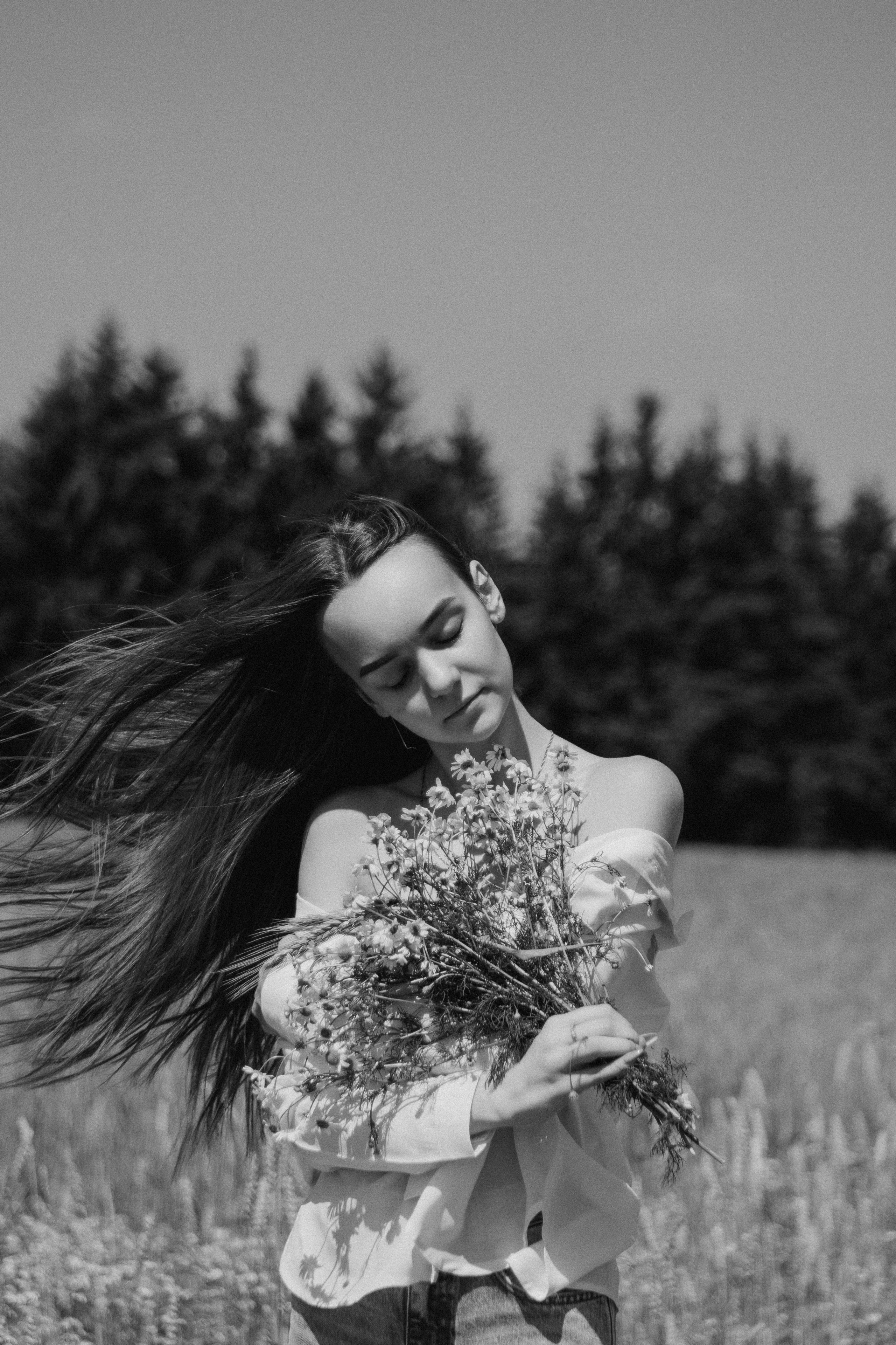 Черно белый портрет девушки в поле с букетом ромашек