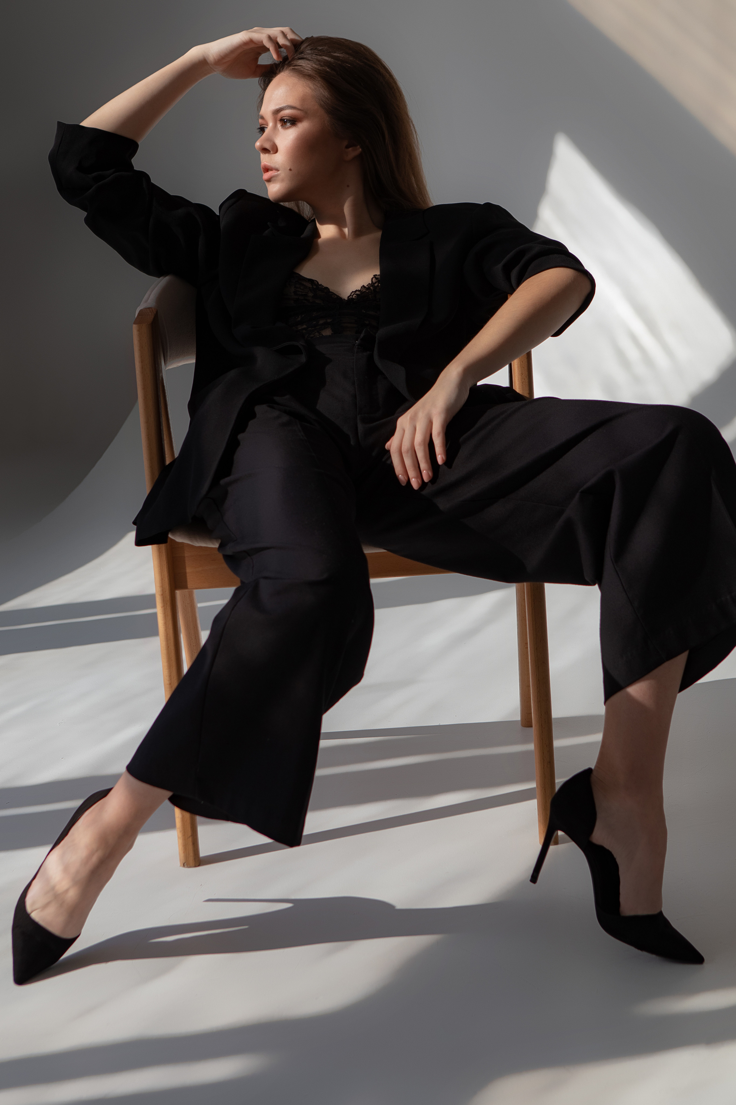 Девушка в черном на стуле на белой циклораме 