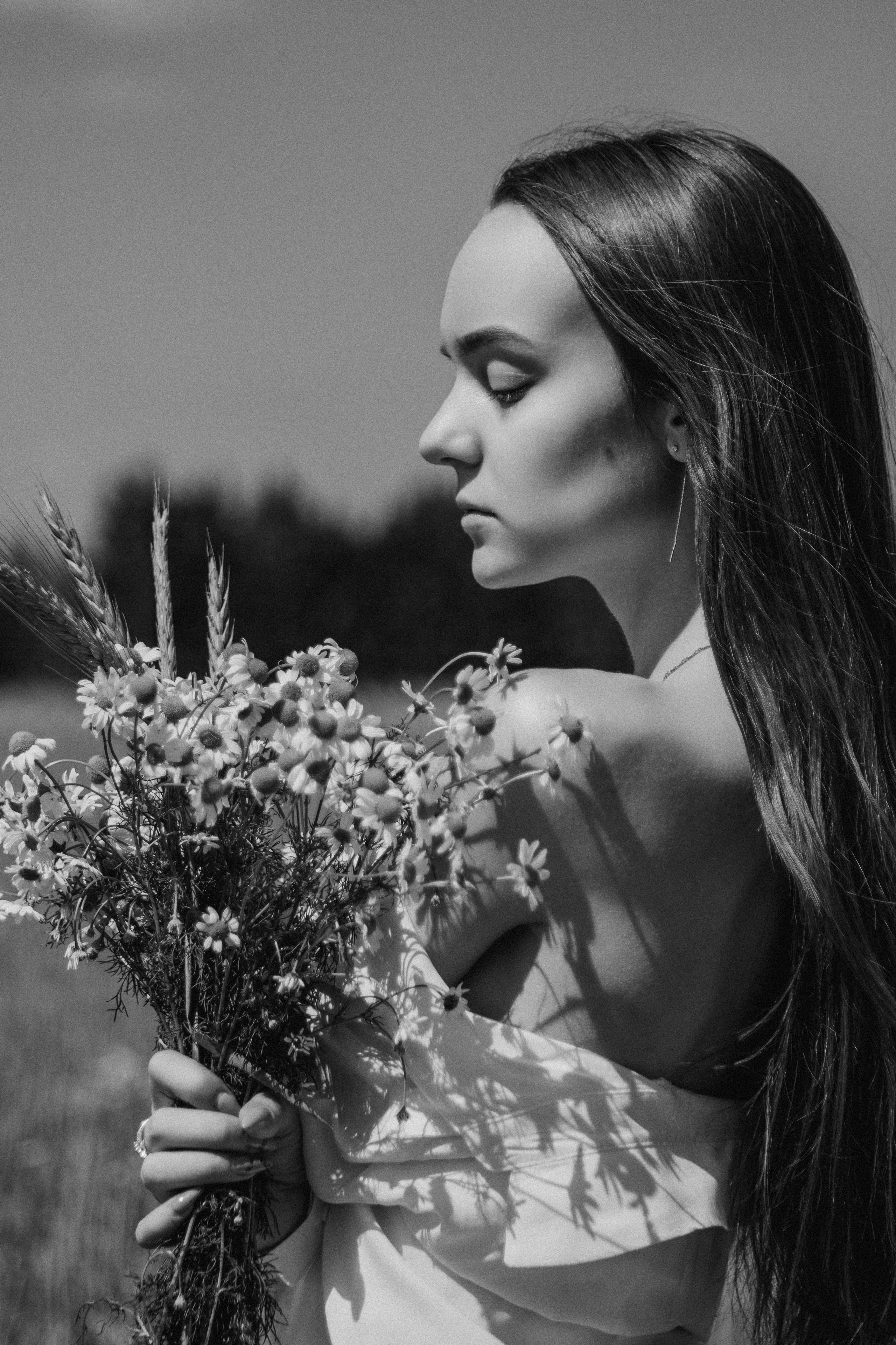 Черно белый портрет девушки в поле с букетом ромашек