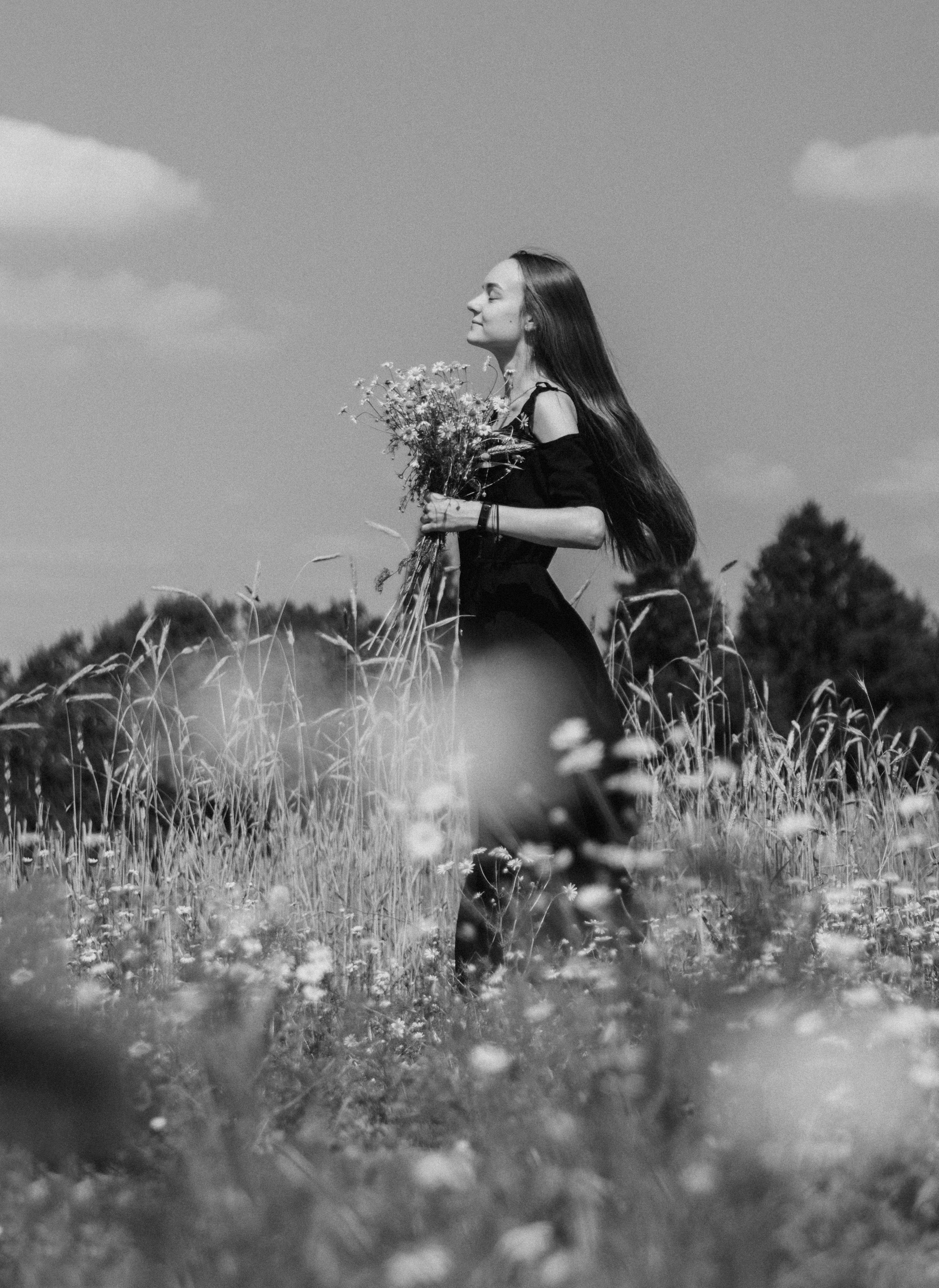 Черно белый портрет девушки в поле с букетом ромашек