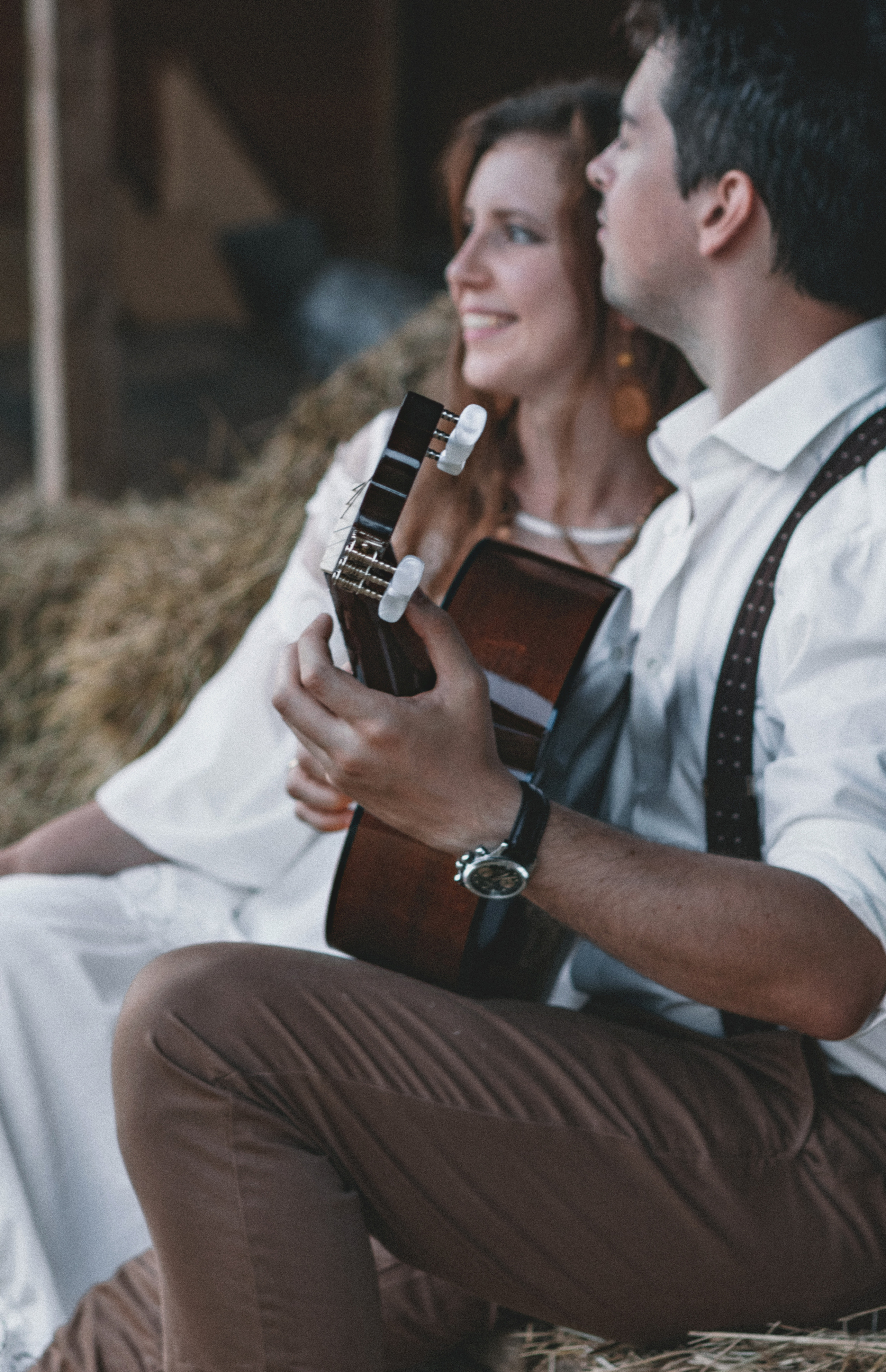 Влюбленная пара в белом играет на гитаре на сеновале