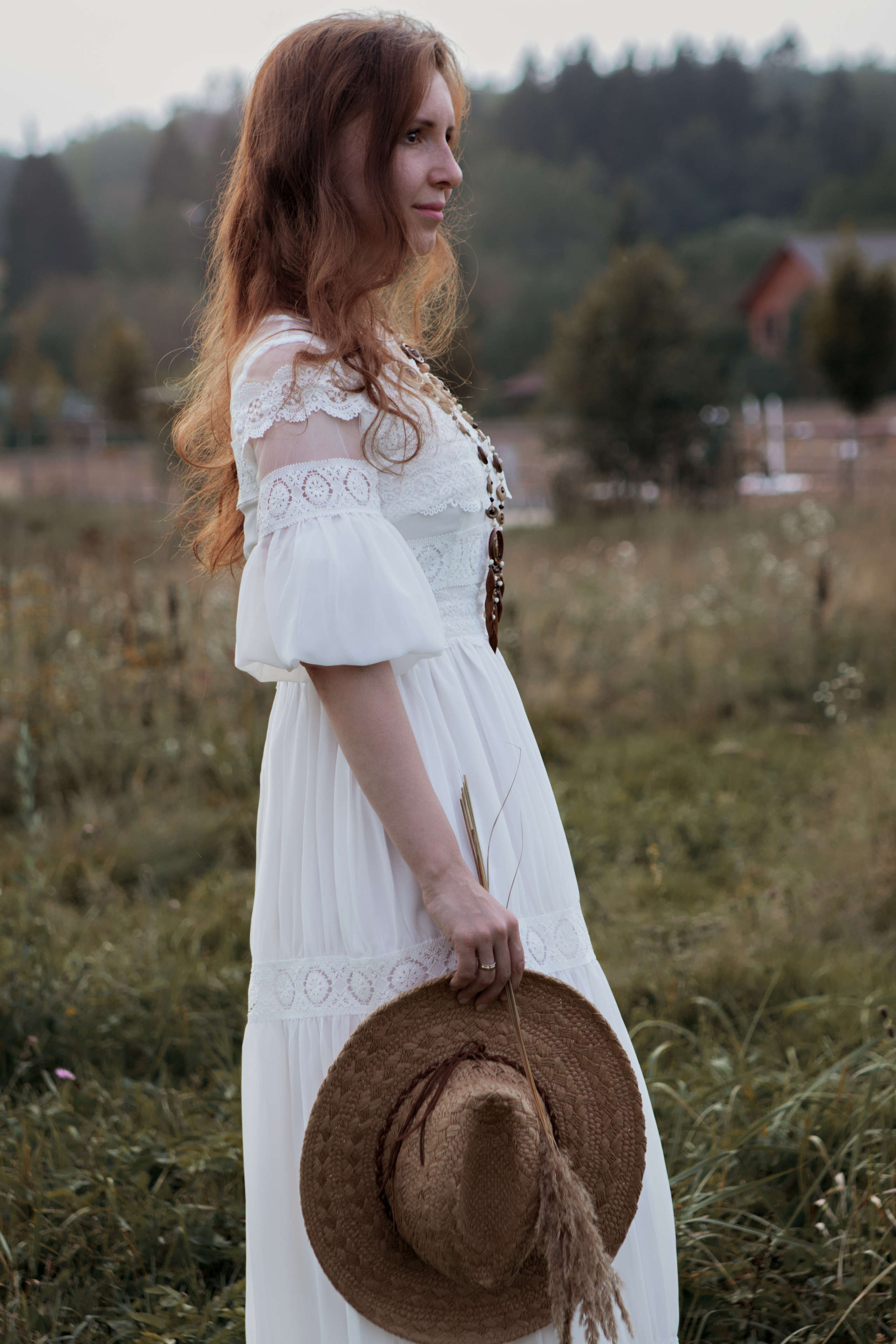 Девушка в белом со шляпой в руке на природе