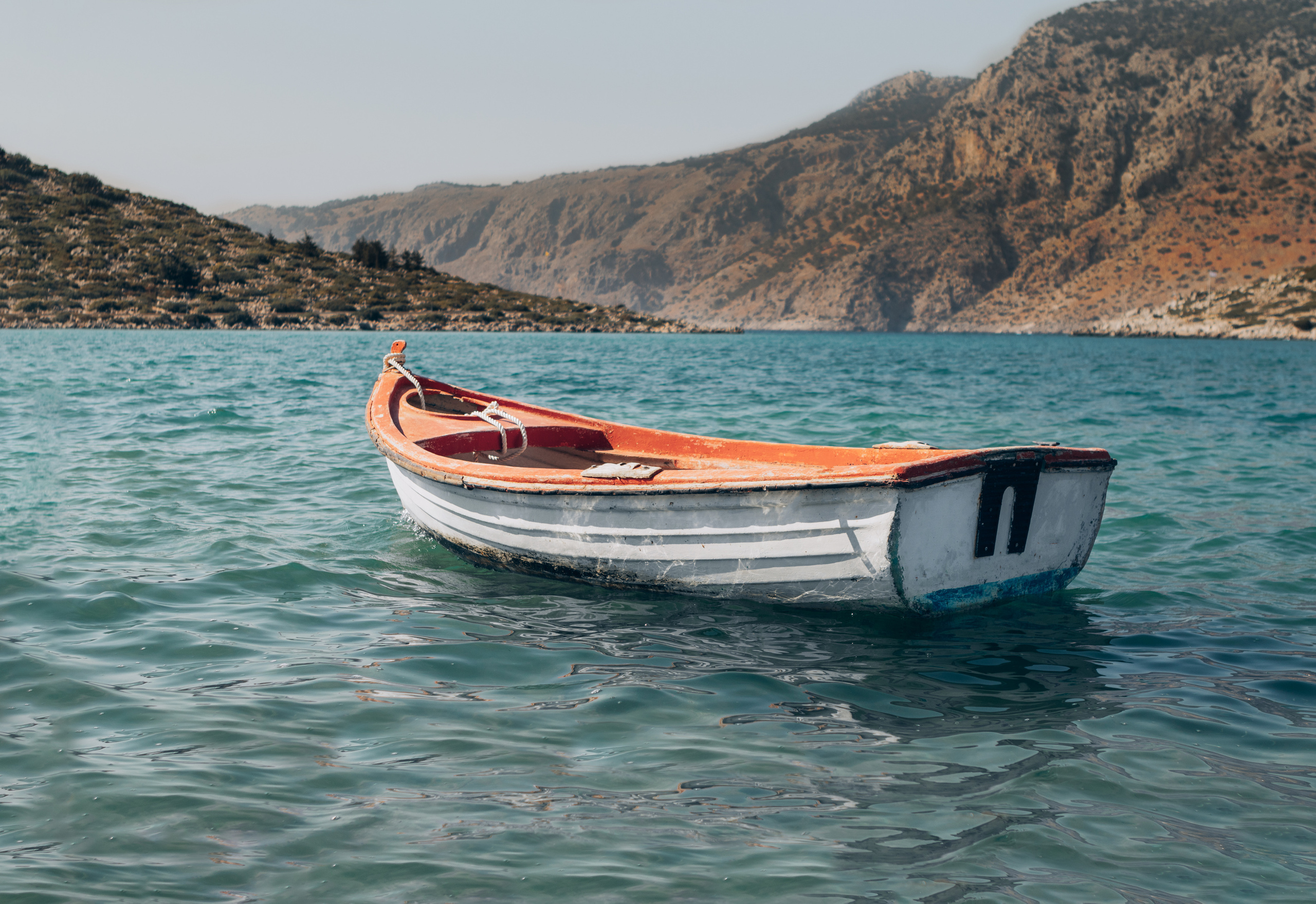 Белая лодка в море на фоне гор