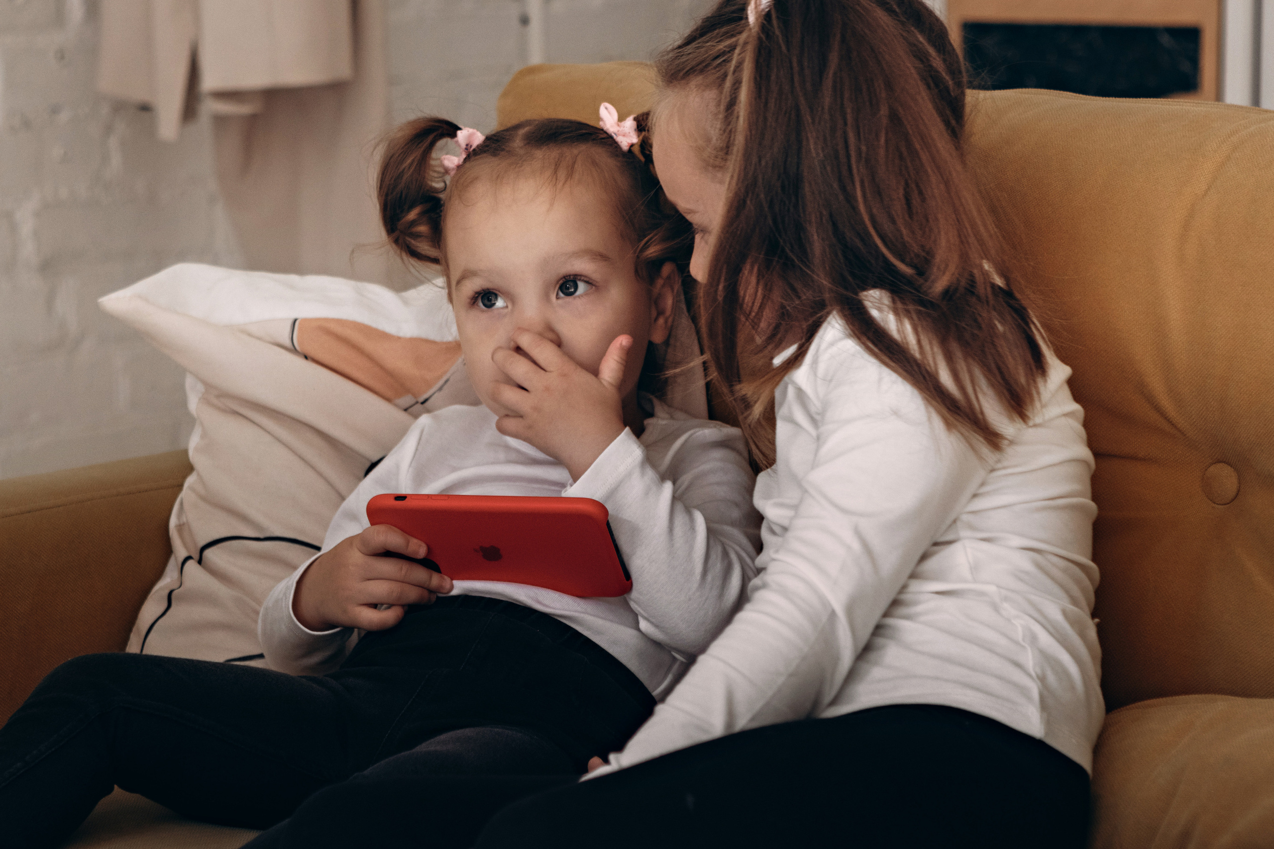 Две маленькие девочки на желтом диване