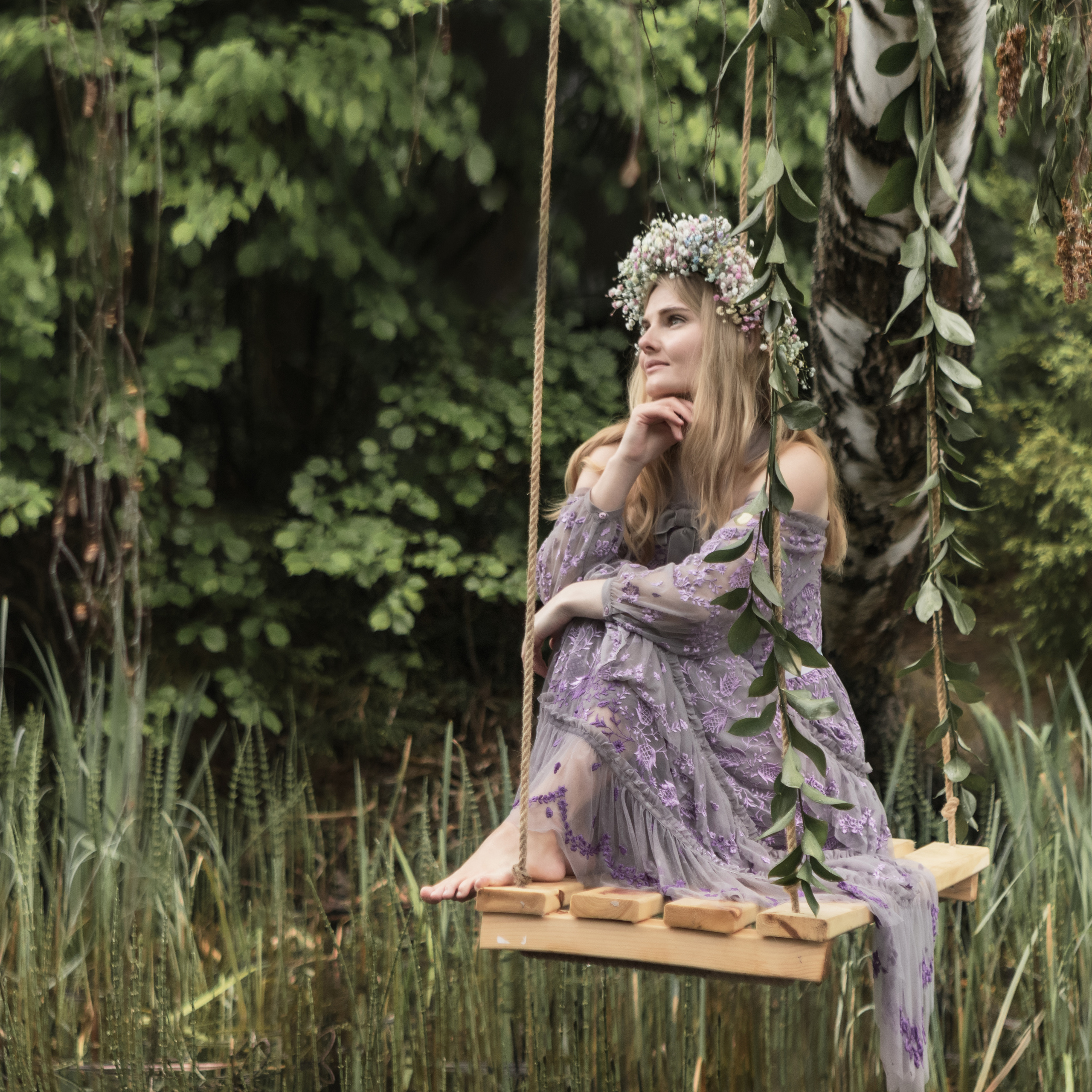 Девушка на качелях над рекой в лесу